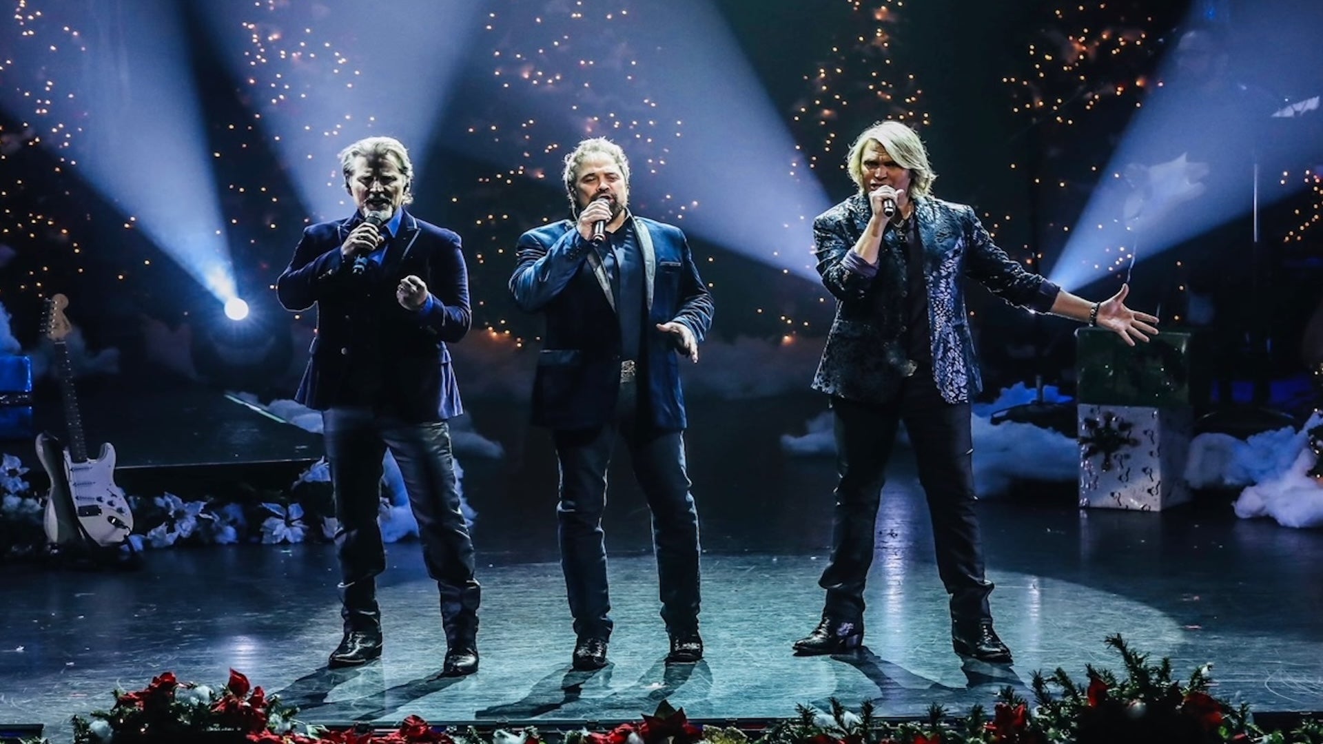 The Texas Tenors on stage singing with shining lights as a background