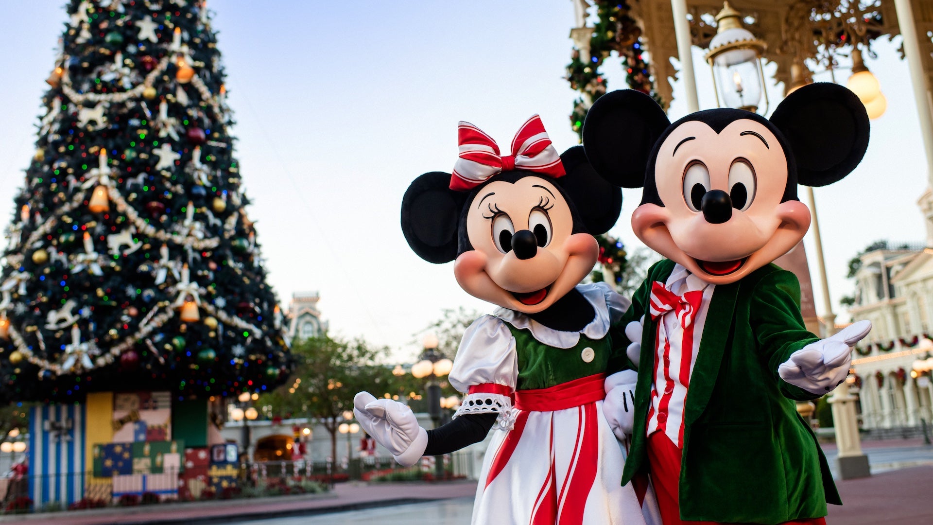 Mickey and Minnie mouse in Christmas attire in front of a Christmas tree at Disney World.