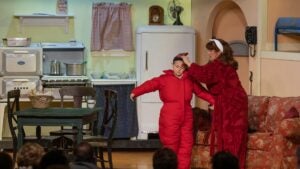 A woman fixes the winter hat of a small boy on the set of A Christmas Story Dinner Show