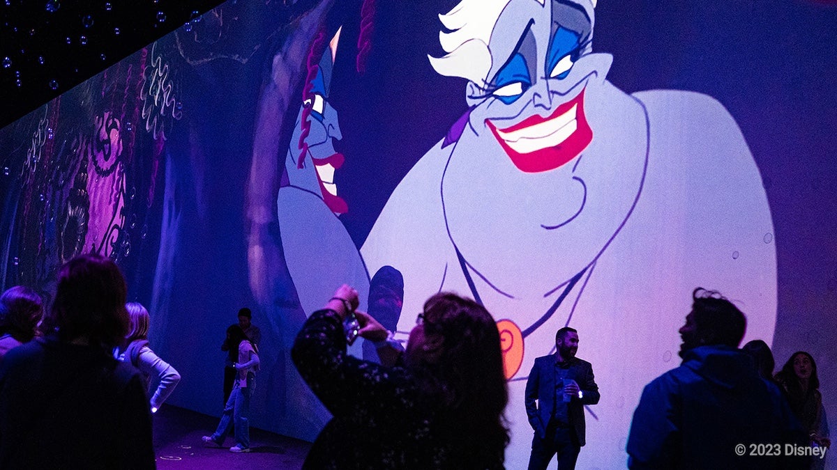 Ursula from The Little Mermaid on a wall while people look on