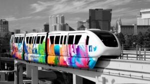 A Las Vegas Monorail train in a "LasVegas.com" wrap travels along with the strip in the background