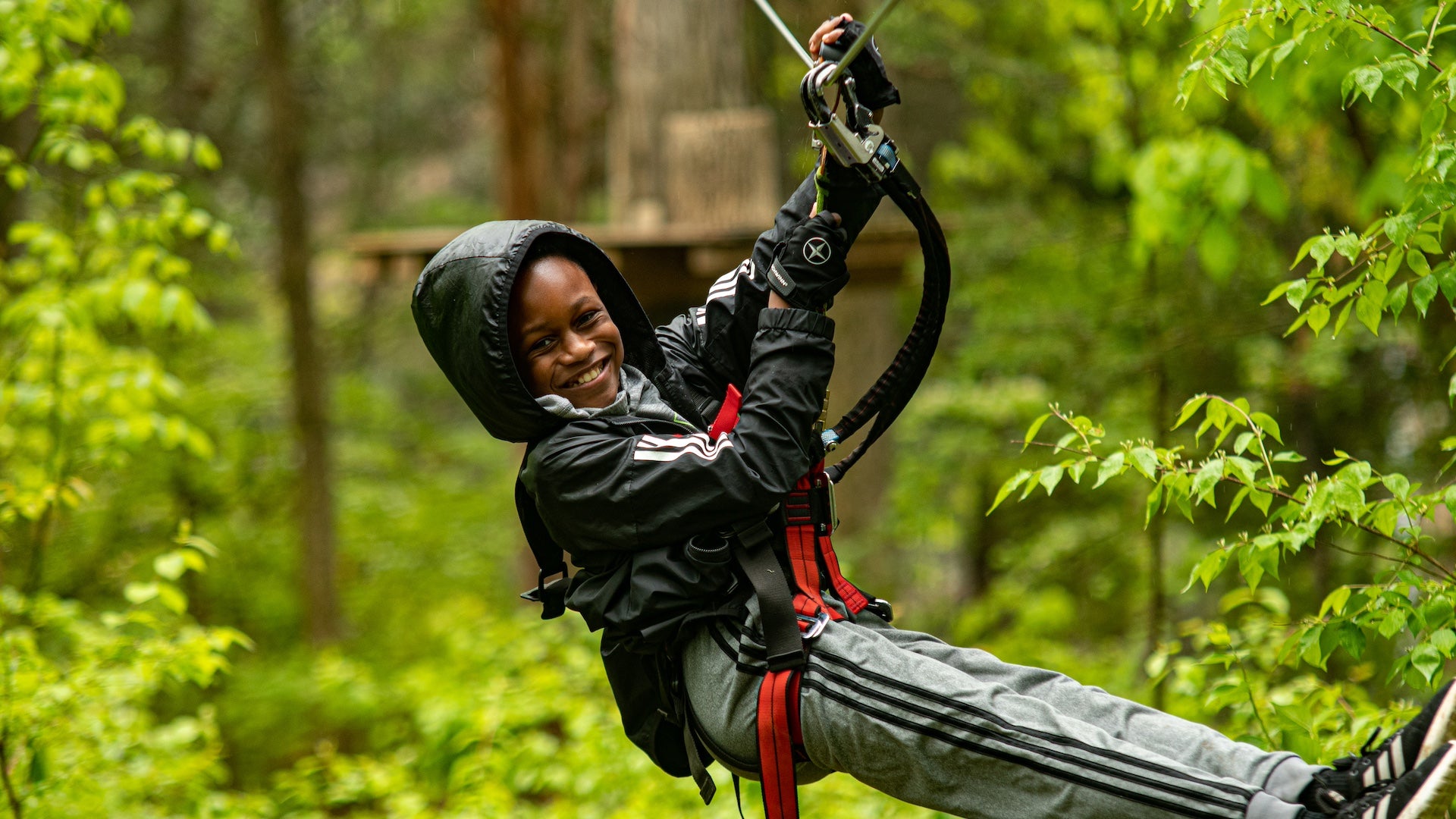 Small boy in a zipline harness smiling at the camera