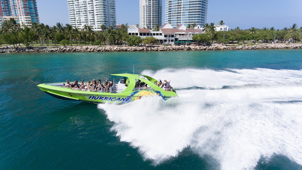 Green thriller speedboat in the water with Miami skyline in the background