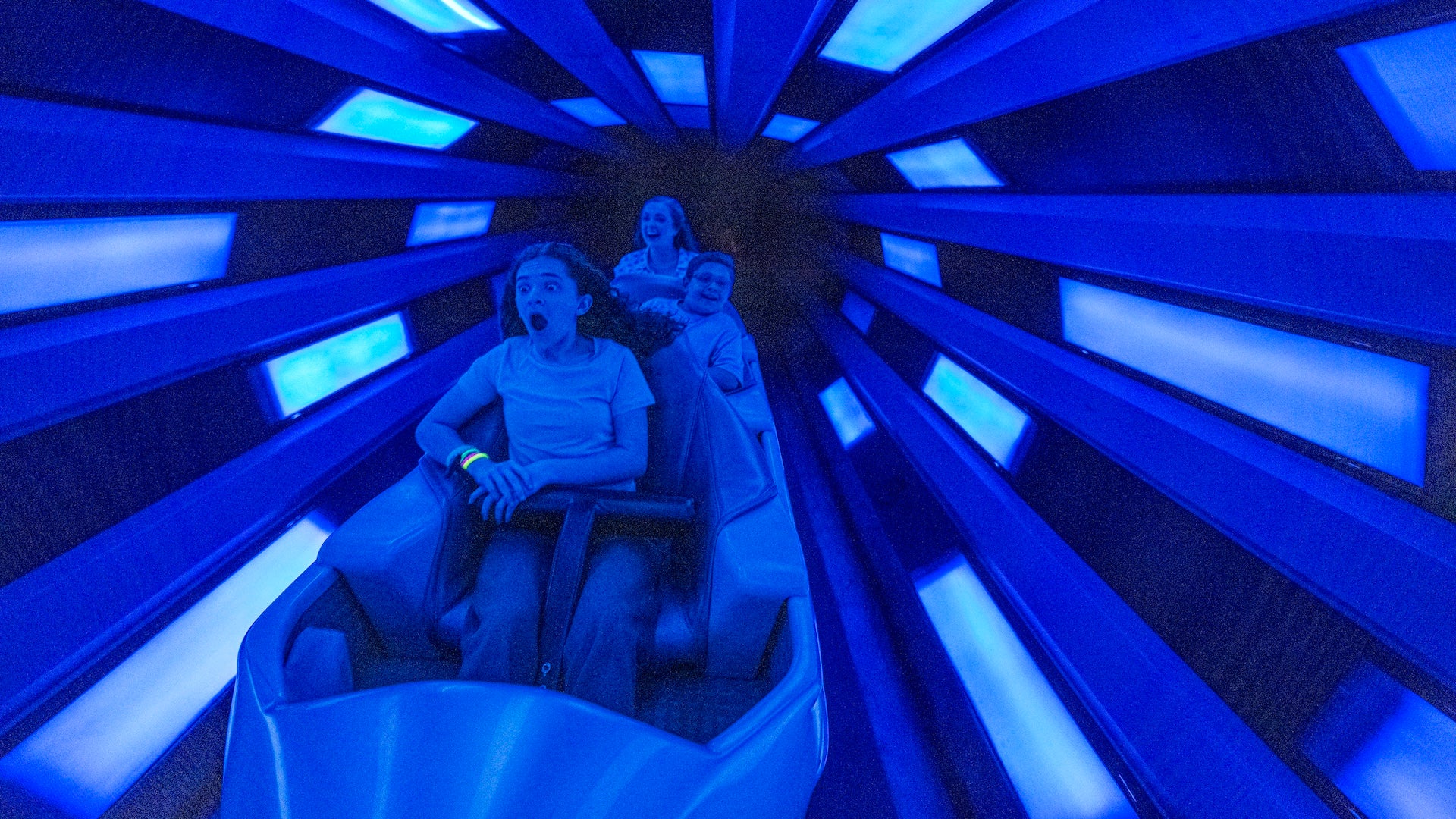 Indoor roller coaster zooming through a galactic themed tunnel