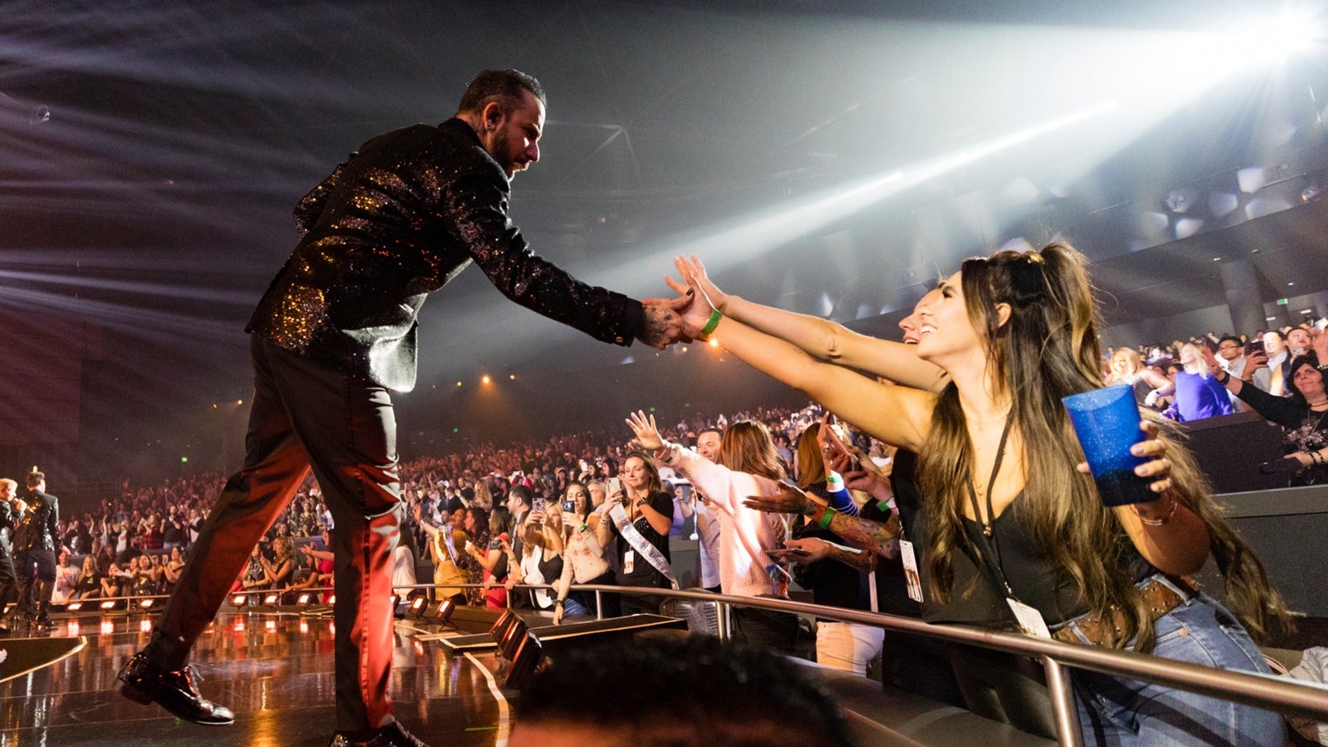 Backstreet Boys on stage reaching out to fans during a show, audience in the back