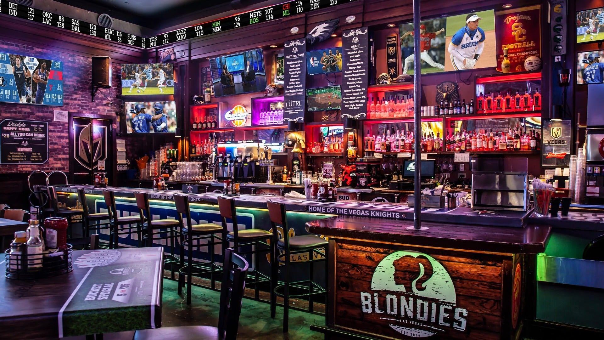 a bar stocked with alcohol, bar counter and chairs, sports posters in the back