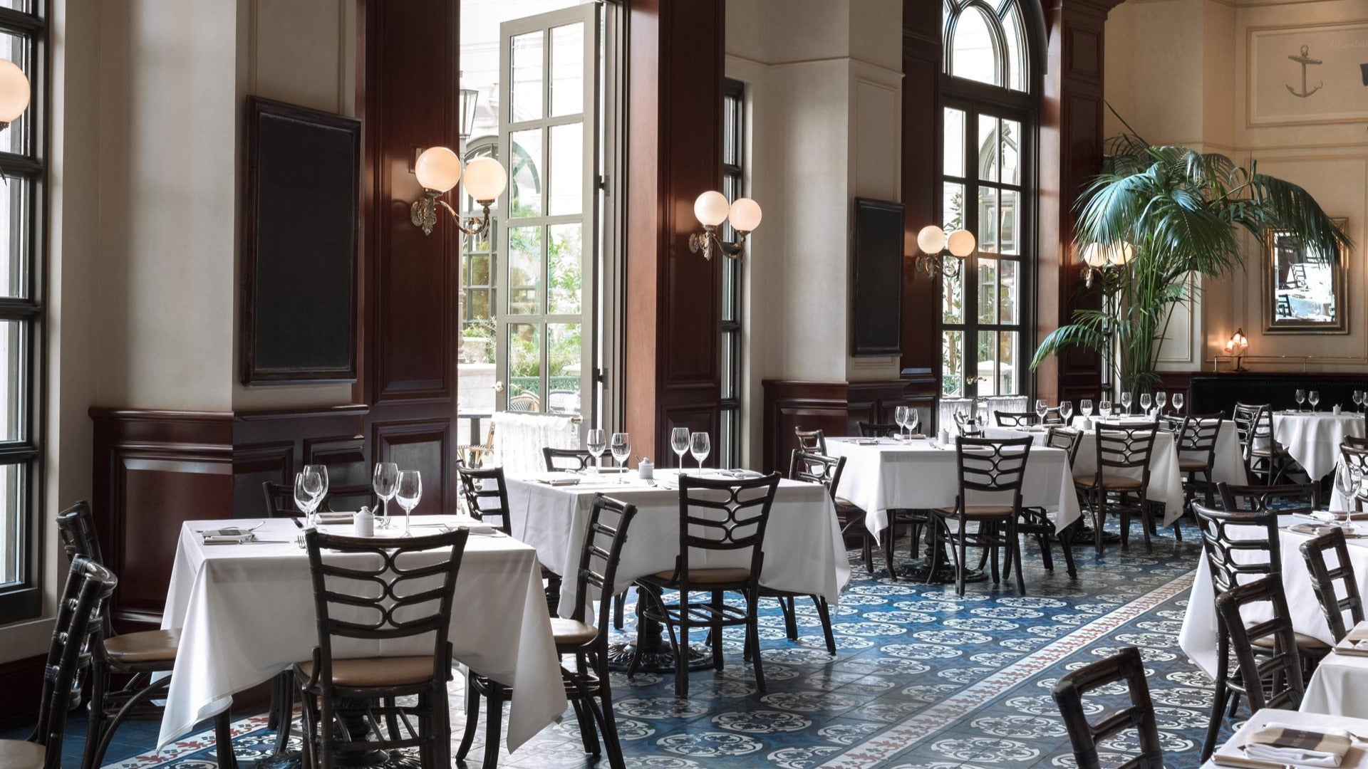 restaurant interior with white tablecloths, dining tables and chairs and big windows, plant in the corner