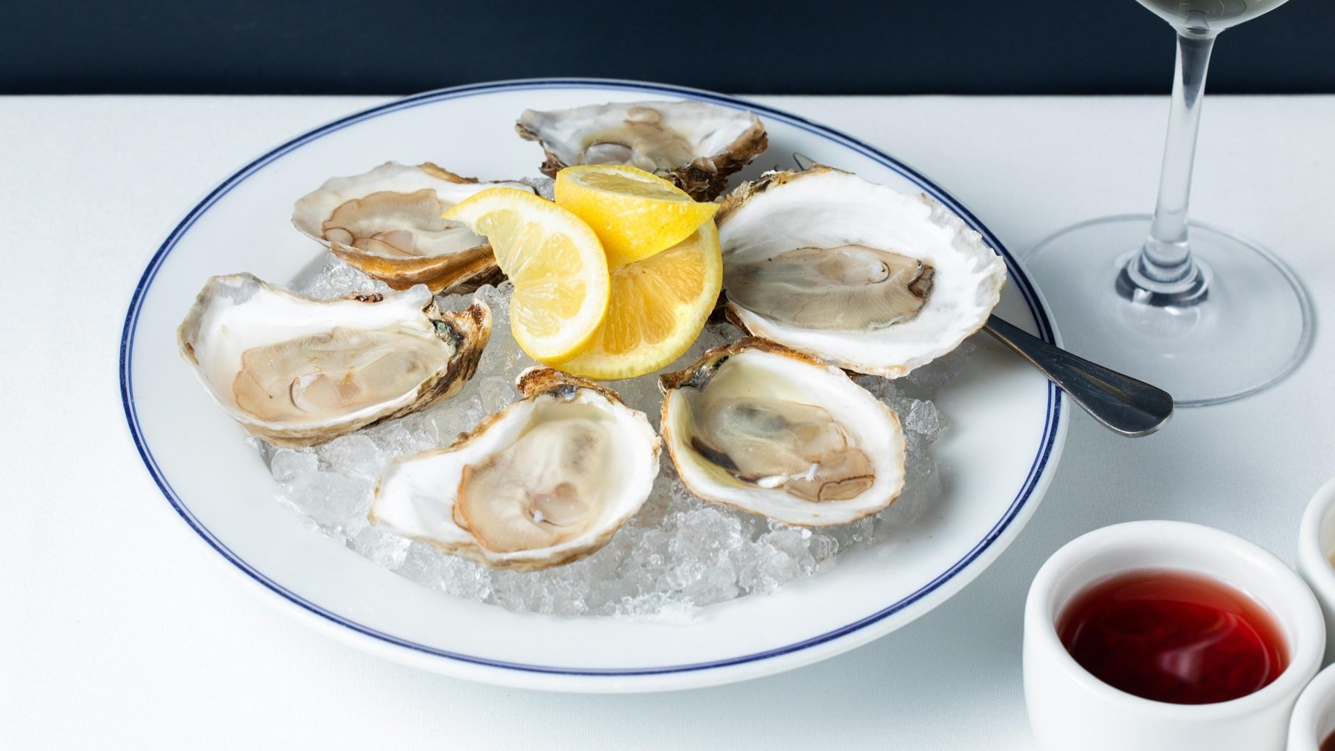 oysters served with melon on a plate, wine glass in the corner