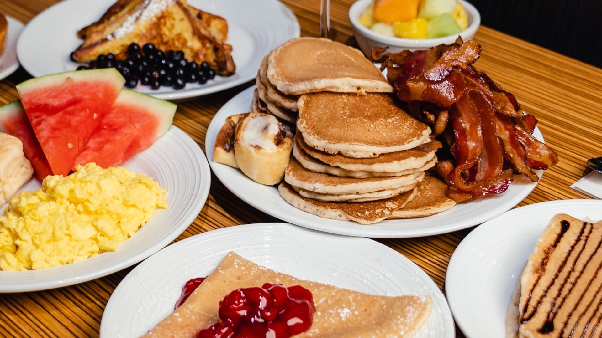 breakfast food on the table, pancakes, bacon, french toast, fruits, and eggs