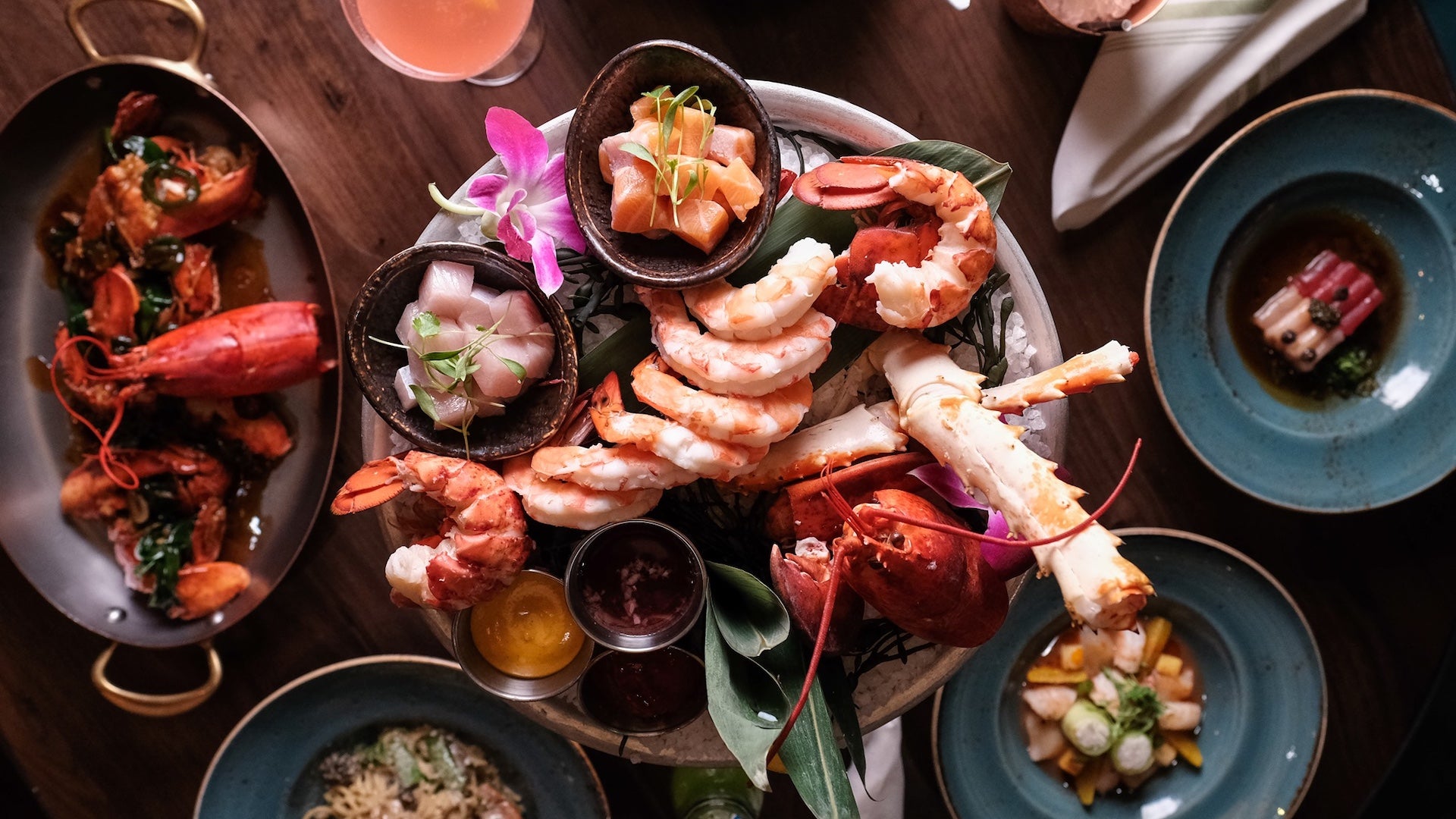 Several blue plates with a variety of seafood dishes on a wooden table