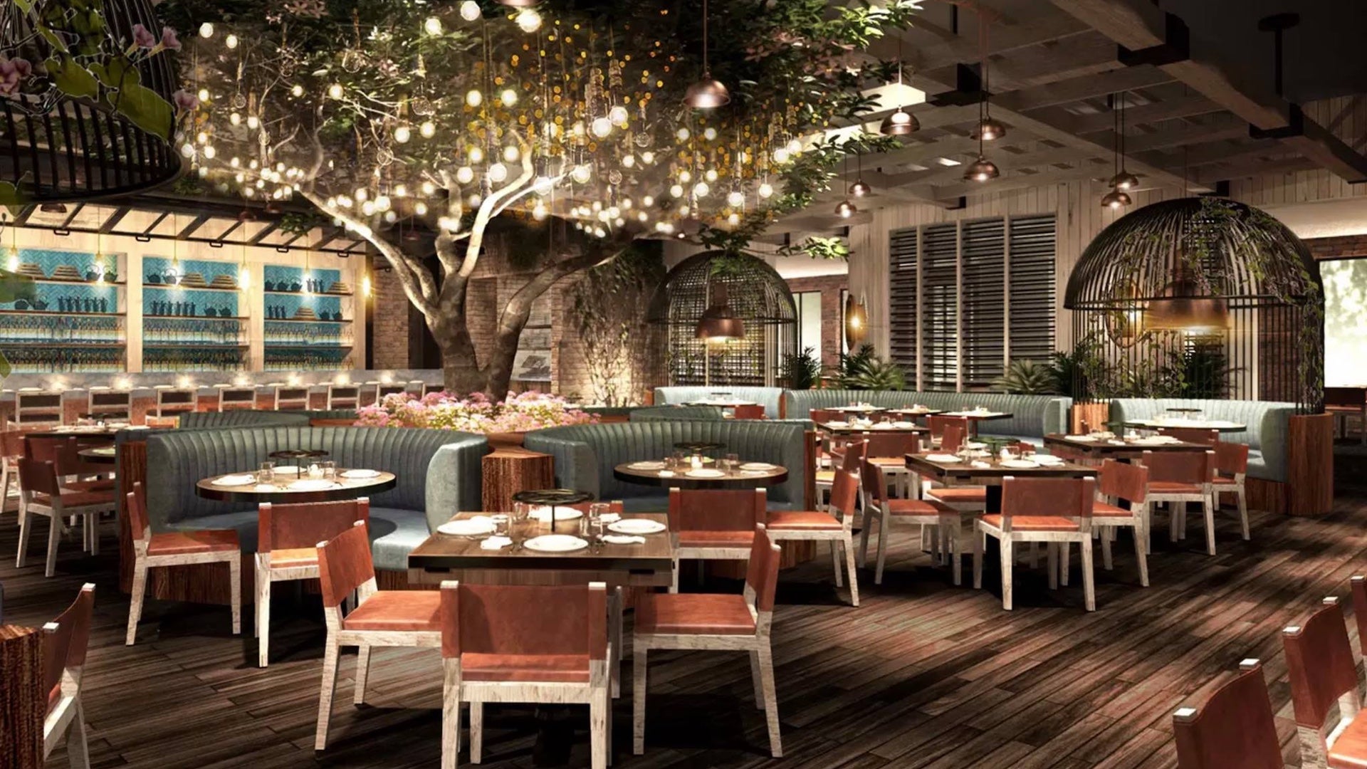 Dining room with orange chairs and green booths there is a large tree in the middle with hanging lights