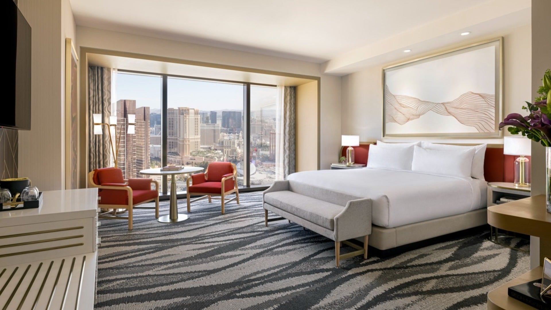 hotel room interior with bed, chairs, carpet, and view of las vegas