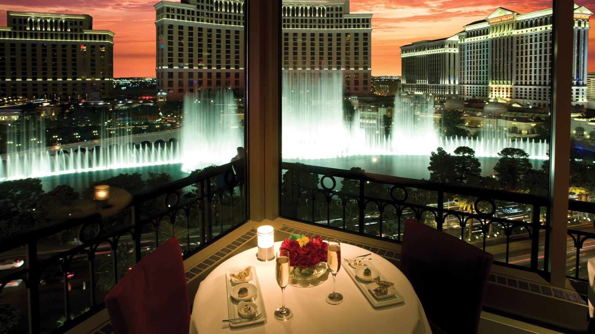 romantic candlelight dinner table at eiffel tower restaurant with a view of the bellagio fountains, sunset