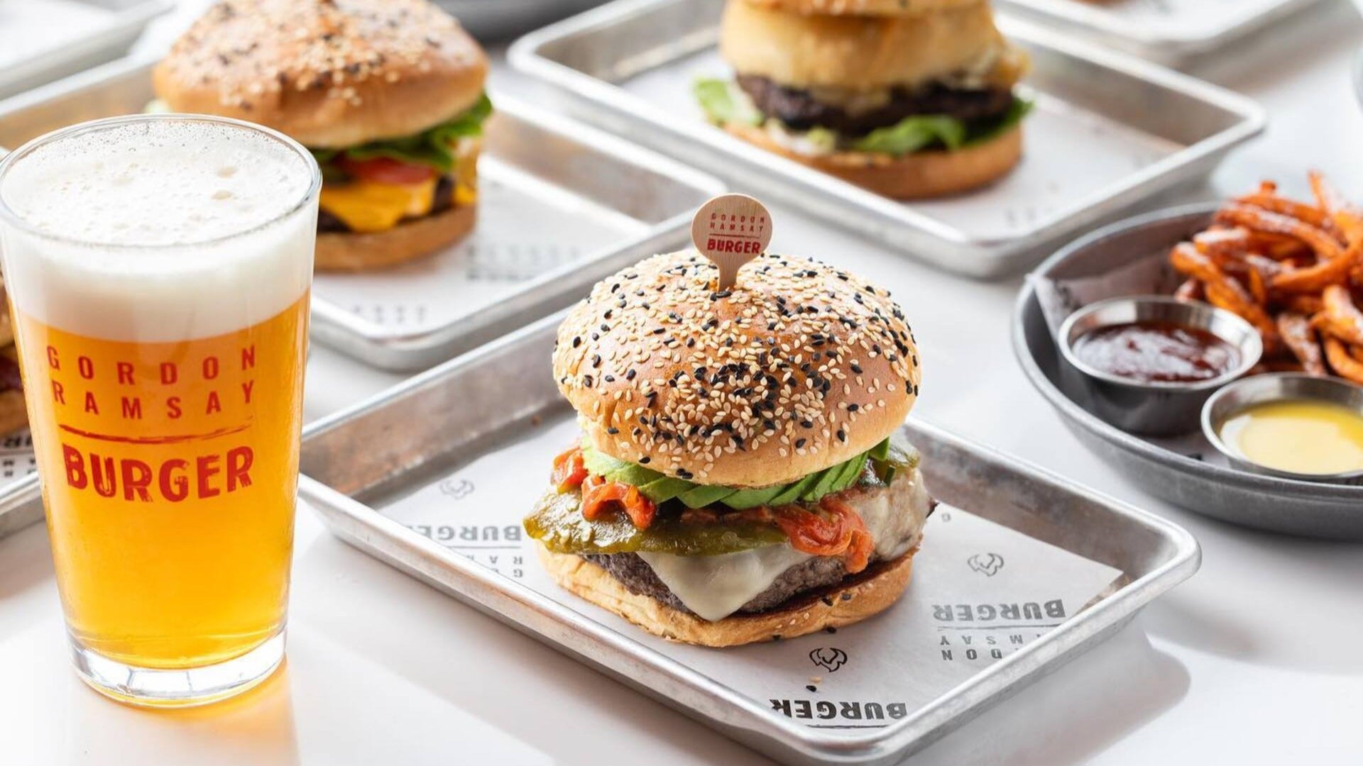 burgers on trays with beer on the side and fries