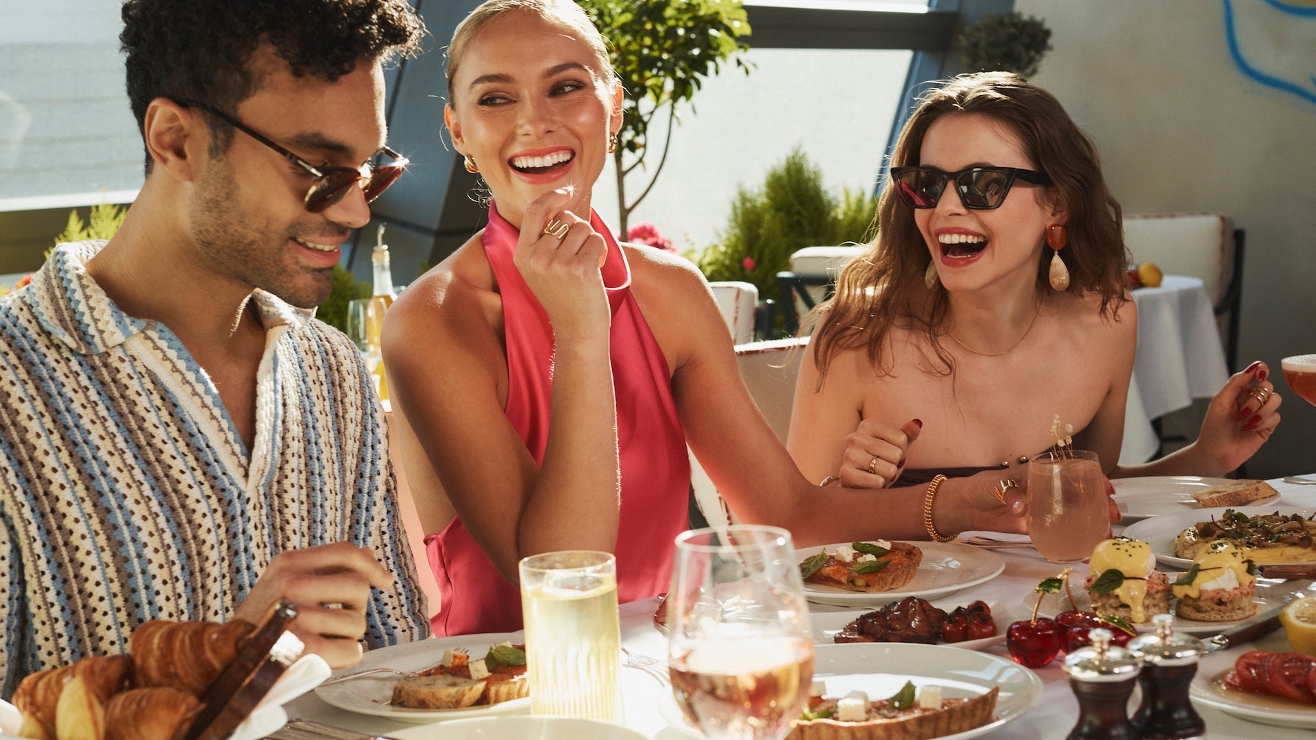 Three people laughing while sitting at a table with breakfast food