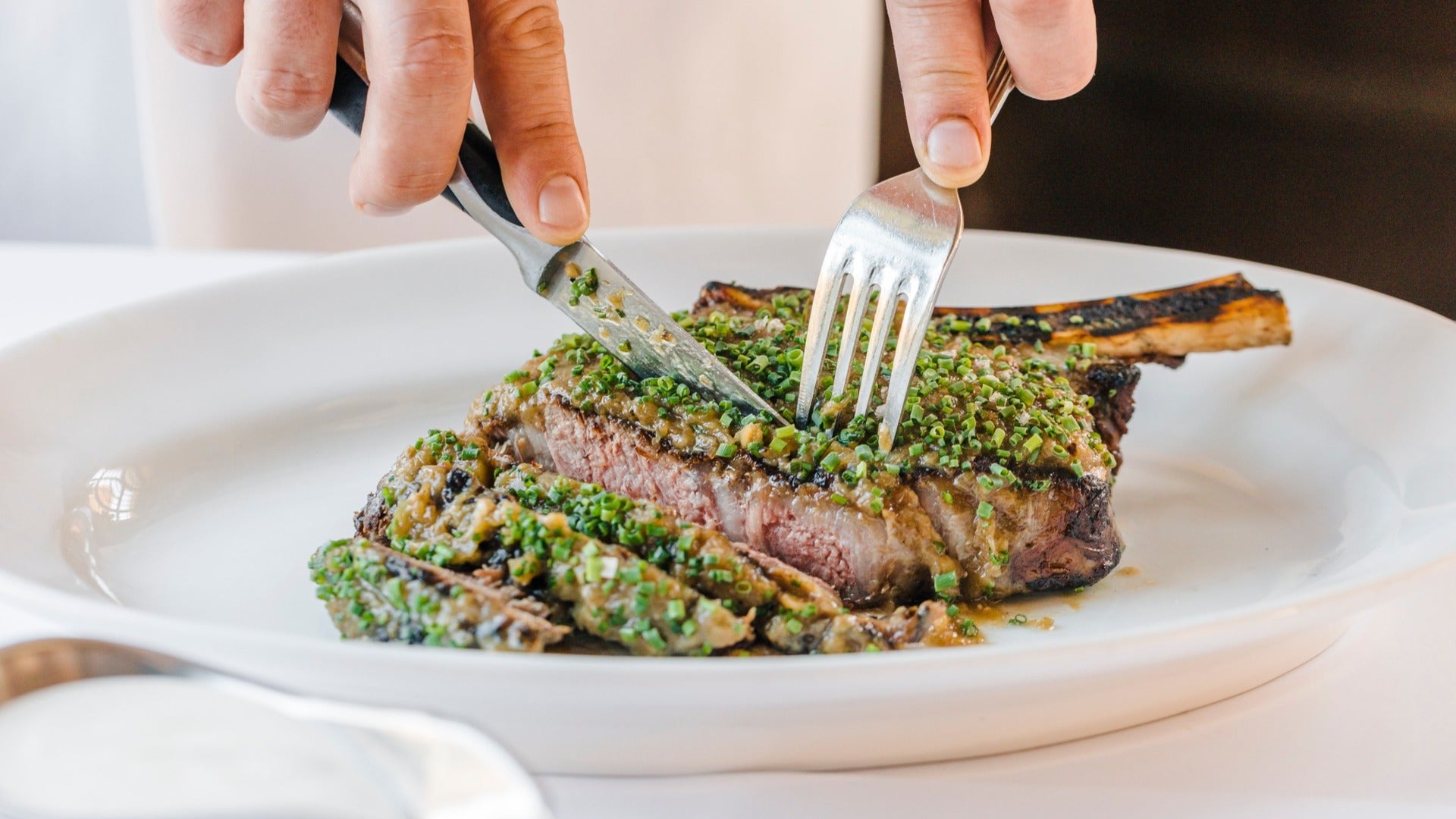 fall menu item at mon ami gabi at paris hotel las vegas, chef cutting through meat with knife and fork