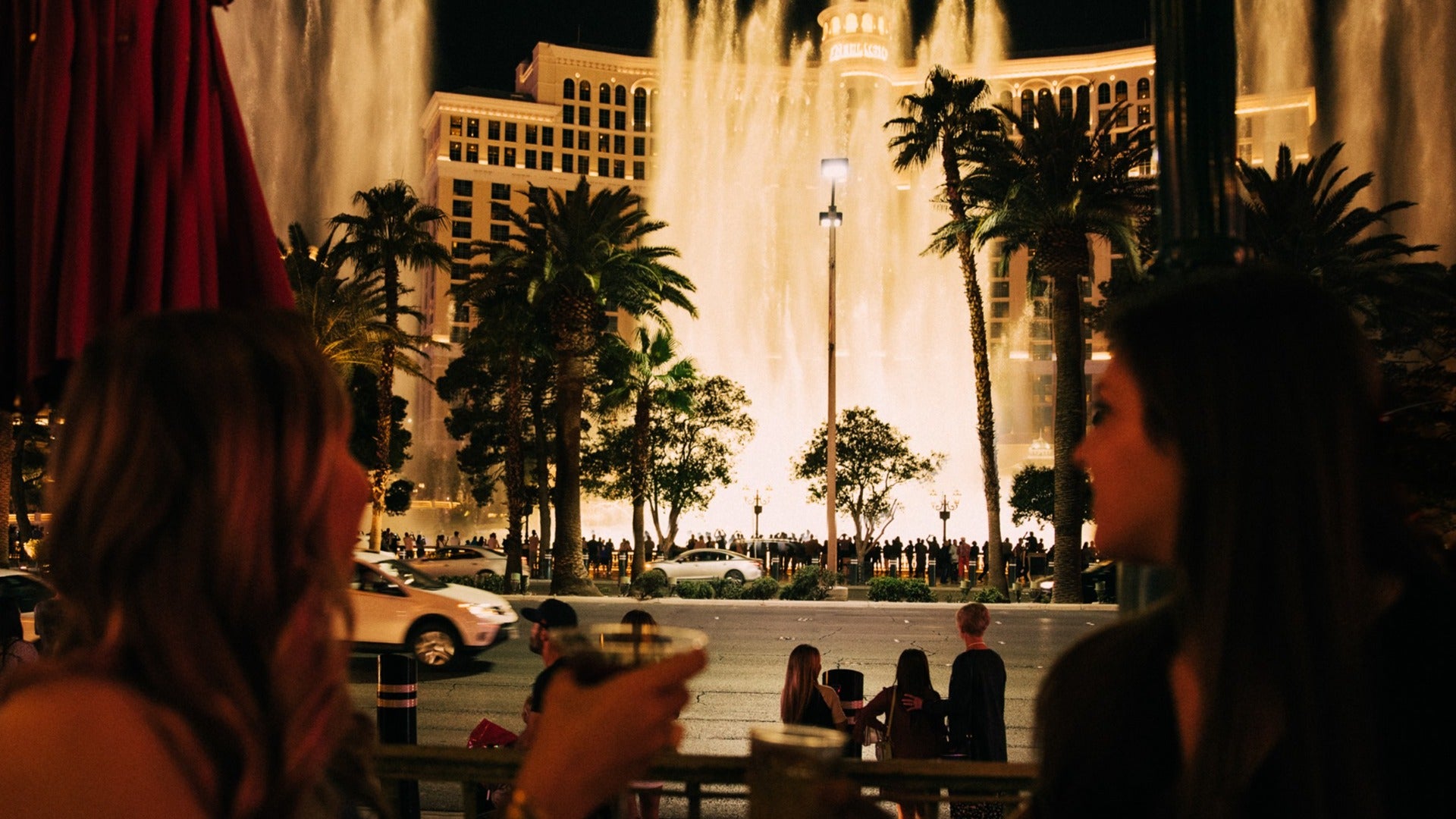 two girls having a drink at mon ami gabi with a view of bellagio fountains at night