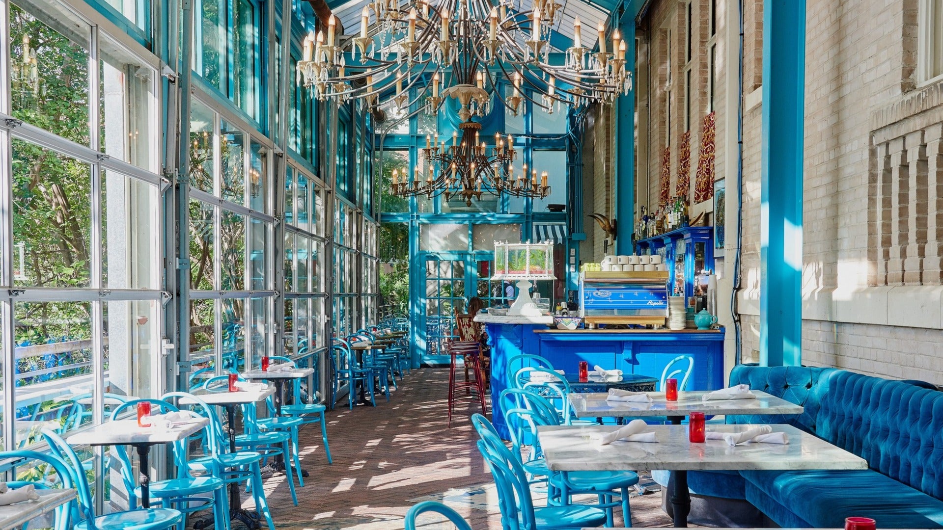 blue dining tables and chairs, restaurant interior, pastries on the counter and chandelier