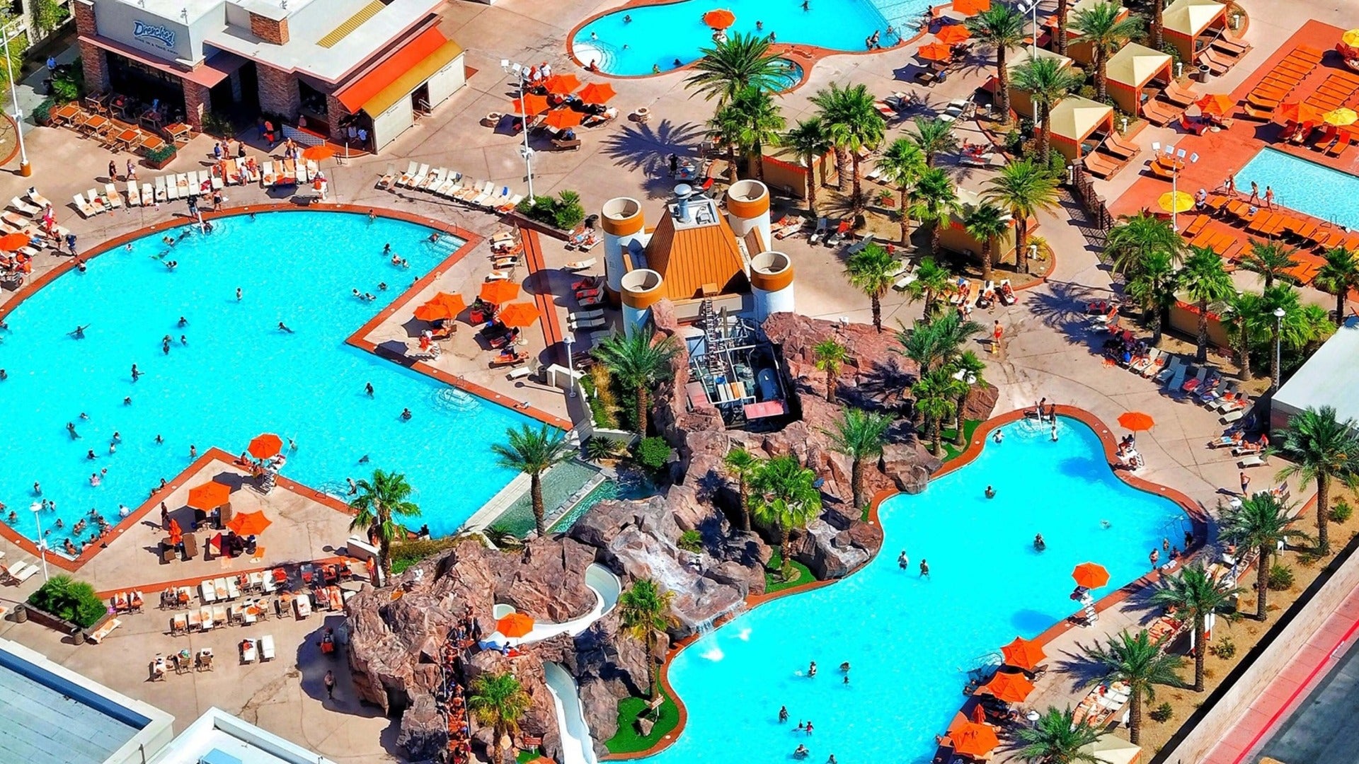 bird's eye view of excalibur hotel pool on a sunny day, groups of people enjoying