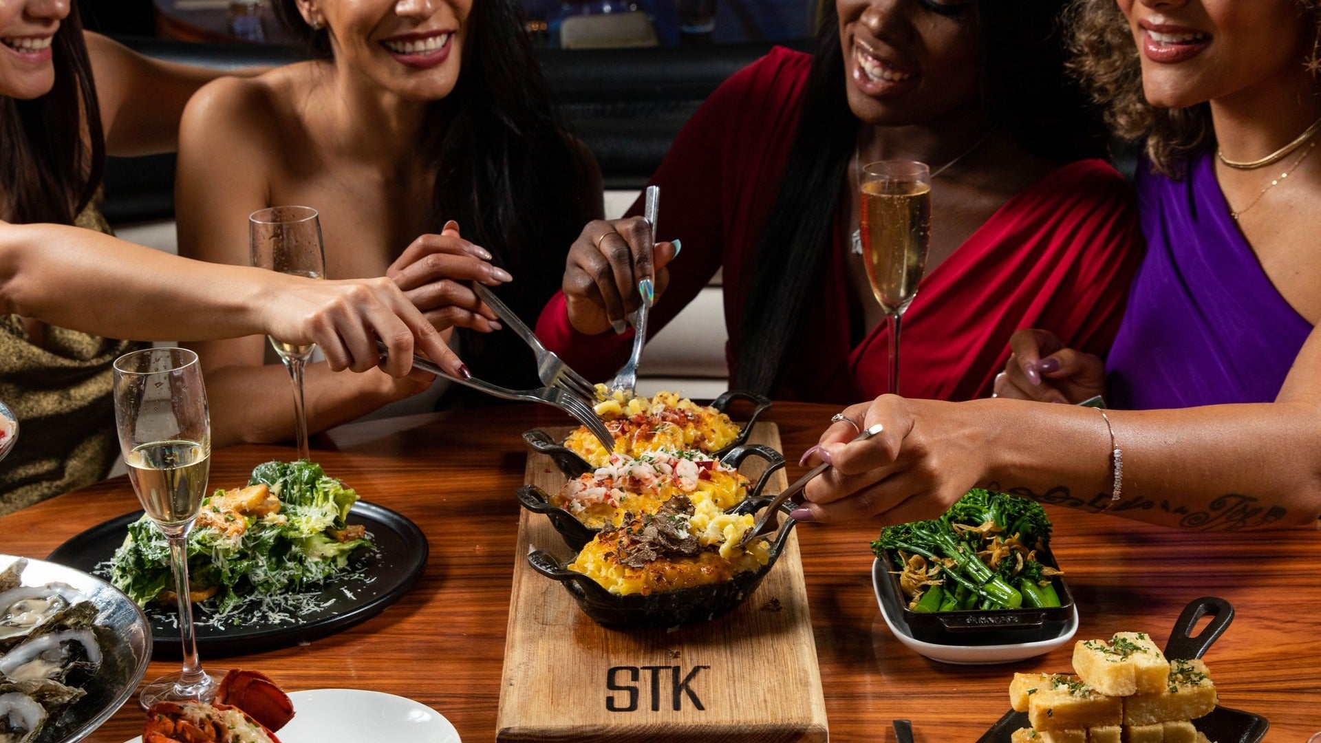 group of friends at stk steakhouse, mac and cheese on a board with side dishes