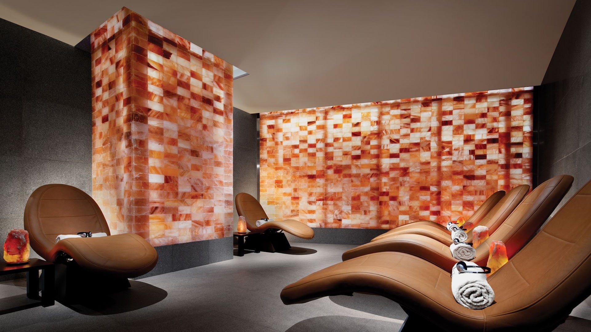 Room with several leather loungers that have towels and headphones on them surrouned by salt walls