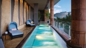 Long narrow pool with blue lounge chairs on the side