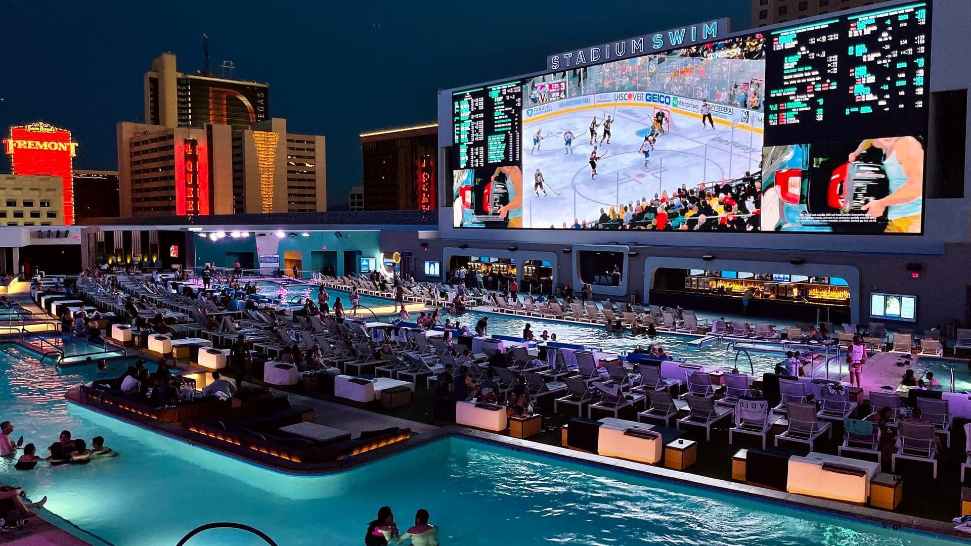 groups of people watching a game of hockey while swimming and drinking