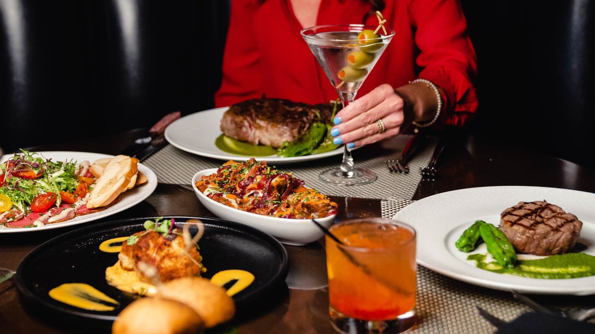 woman enjoying dinner, with cocktails, steak