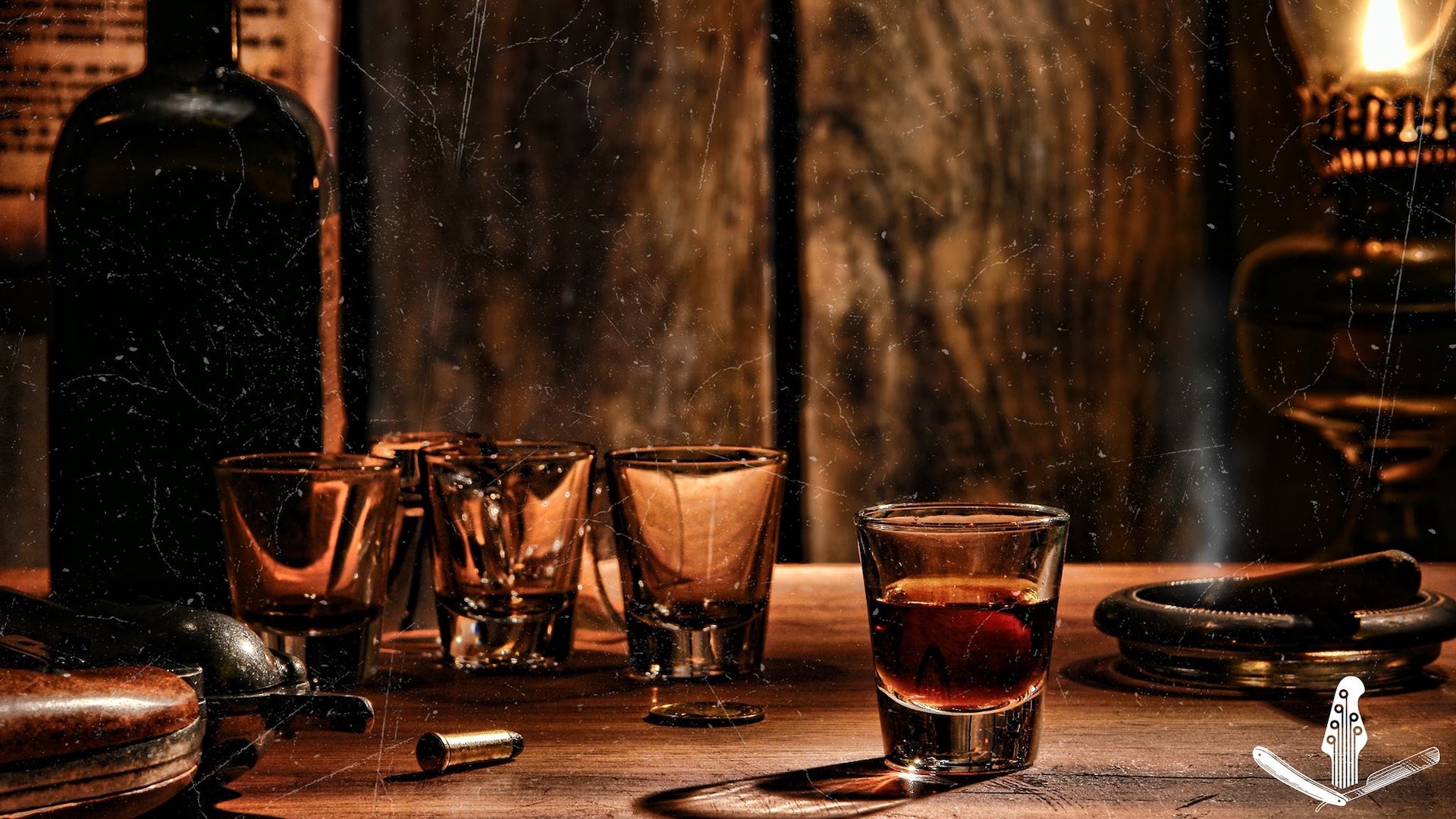 A table with four shot glasses filled with alcohol there is a oil lamp lit in the background and a bottle of alcohol