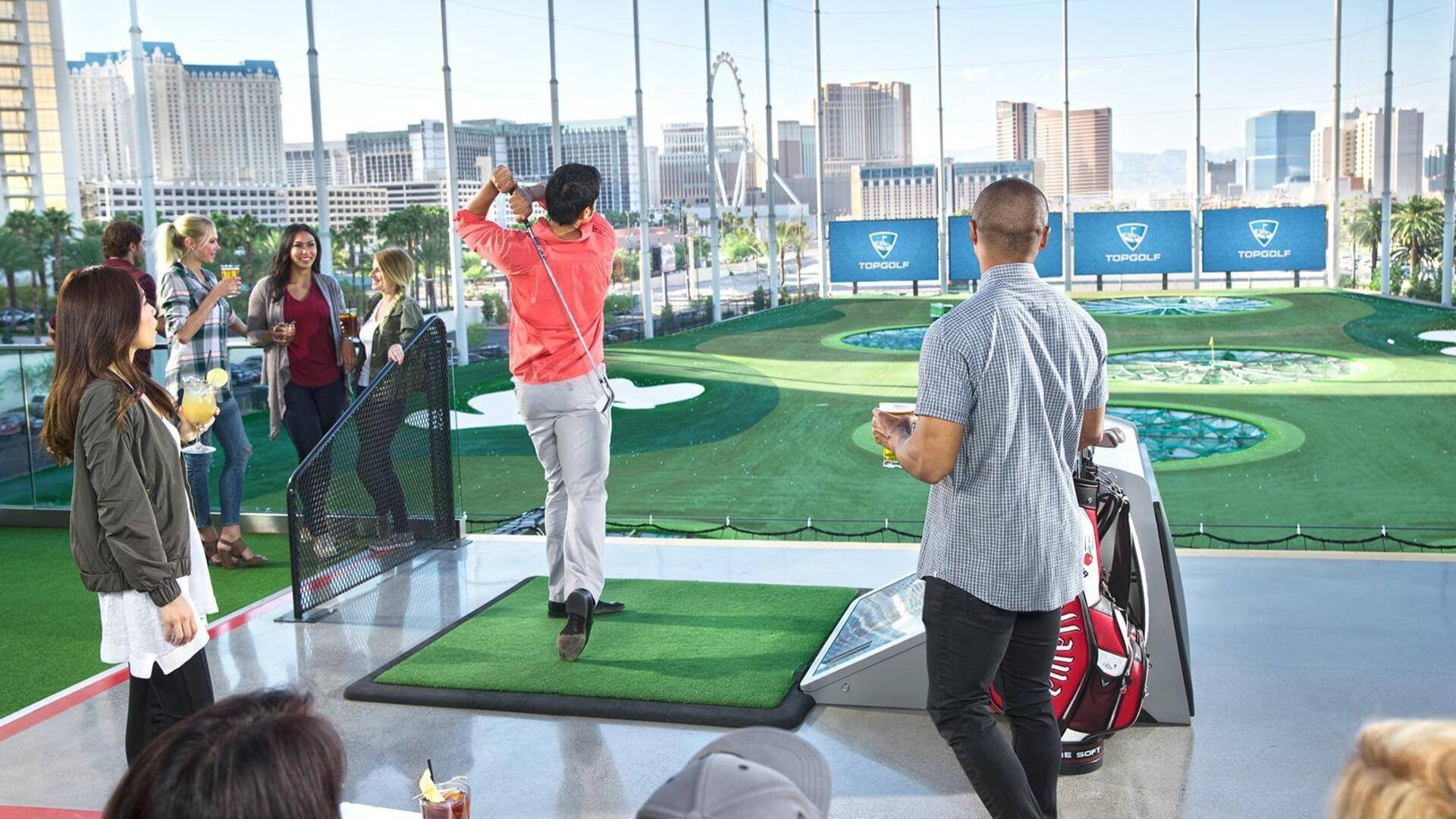 group of friends having fun, playing golf, teeing off at a hitting bay