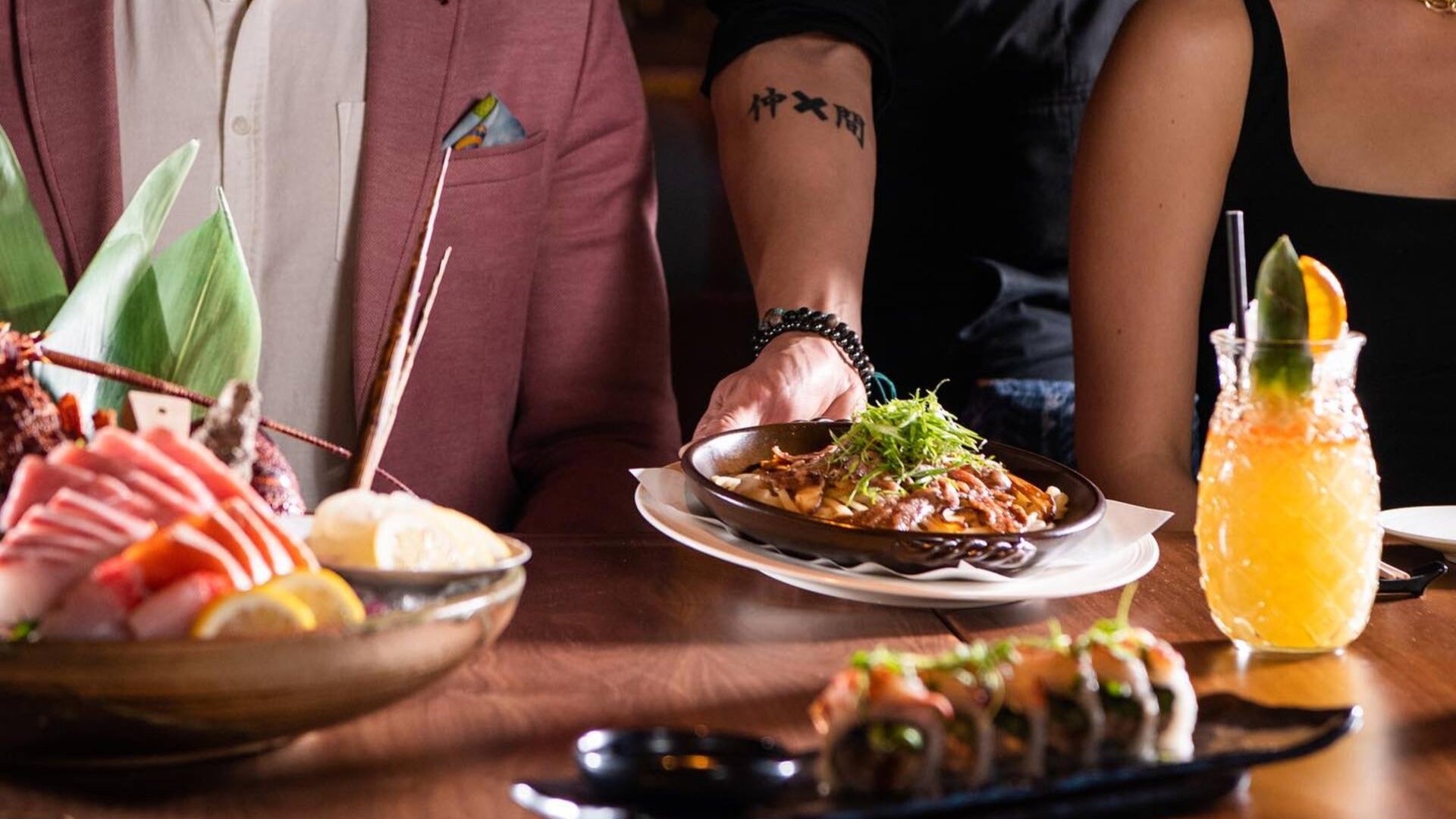 waiter serving a dish to a customer, food on the table and drinks on the side