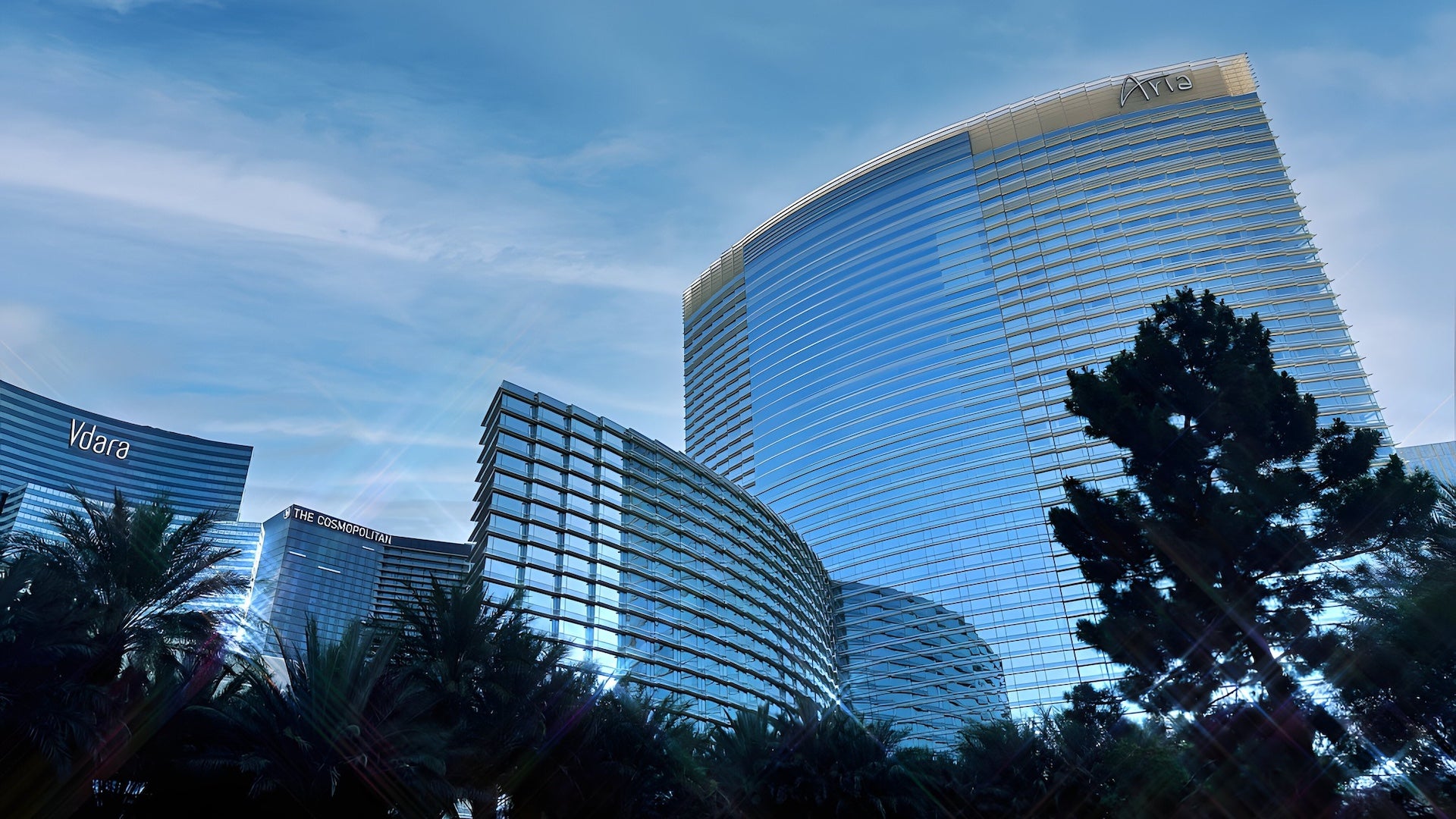 External view of a hotel with trees in the foreground under a blue sky