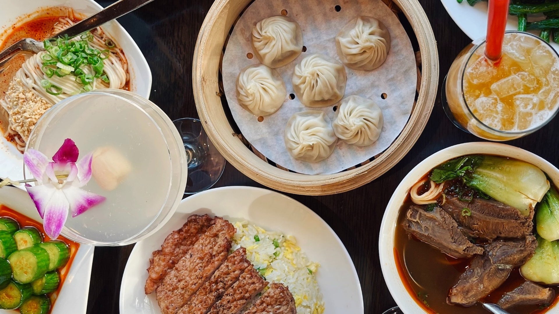 A table with multiple plates of asian food including dumplings, katsu chicken, ramen, and beef