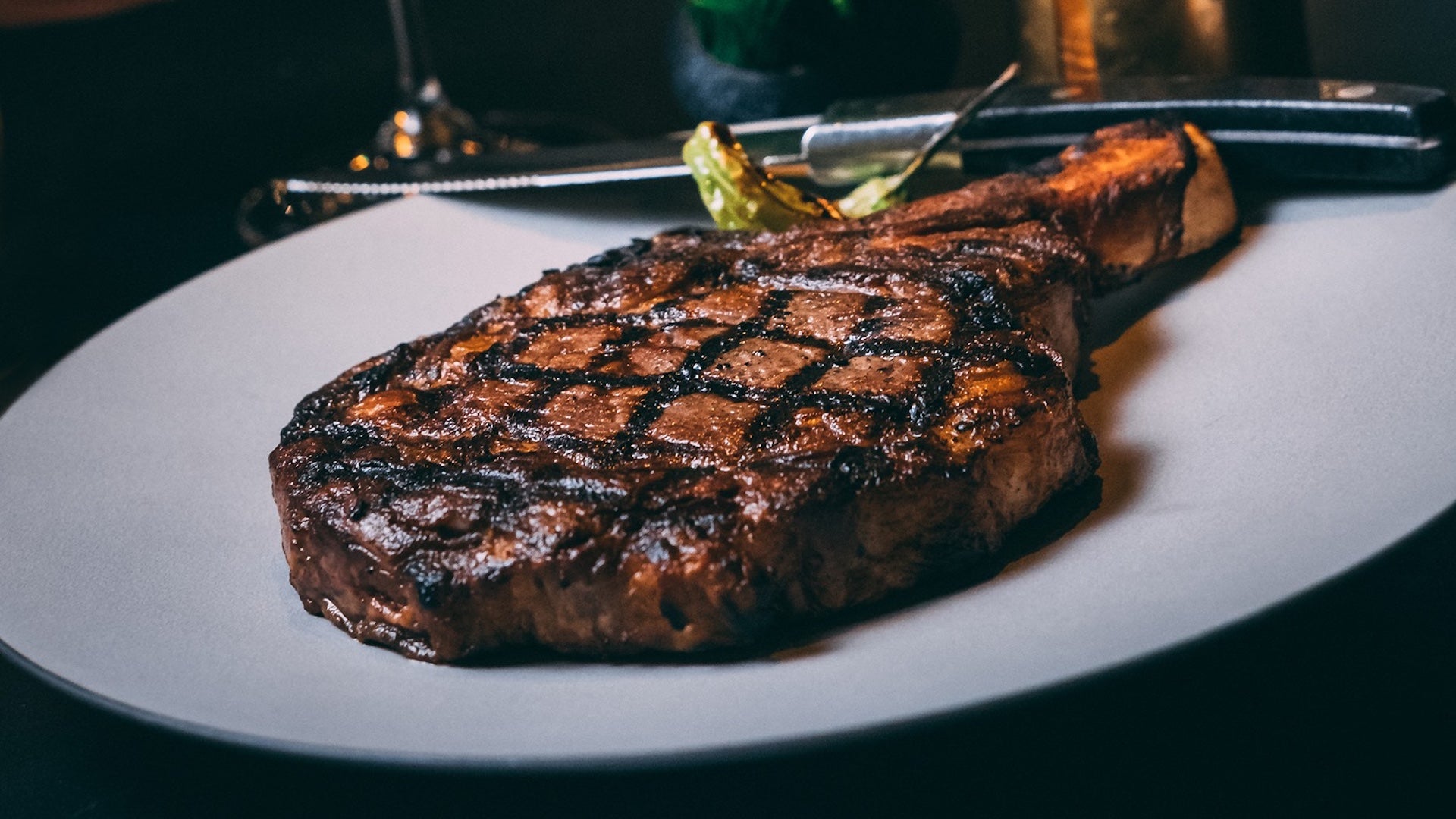 Steak on a white plate with a knife and fork nearby