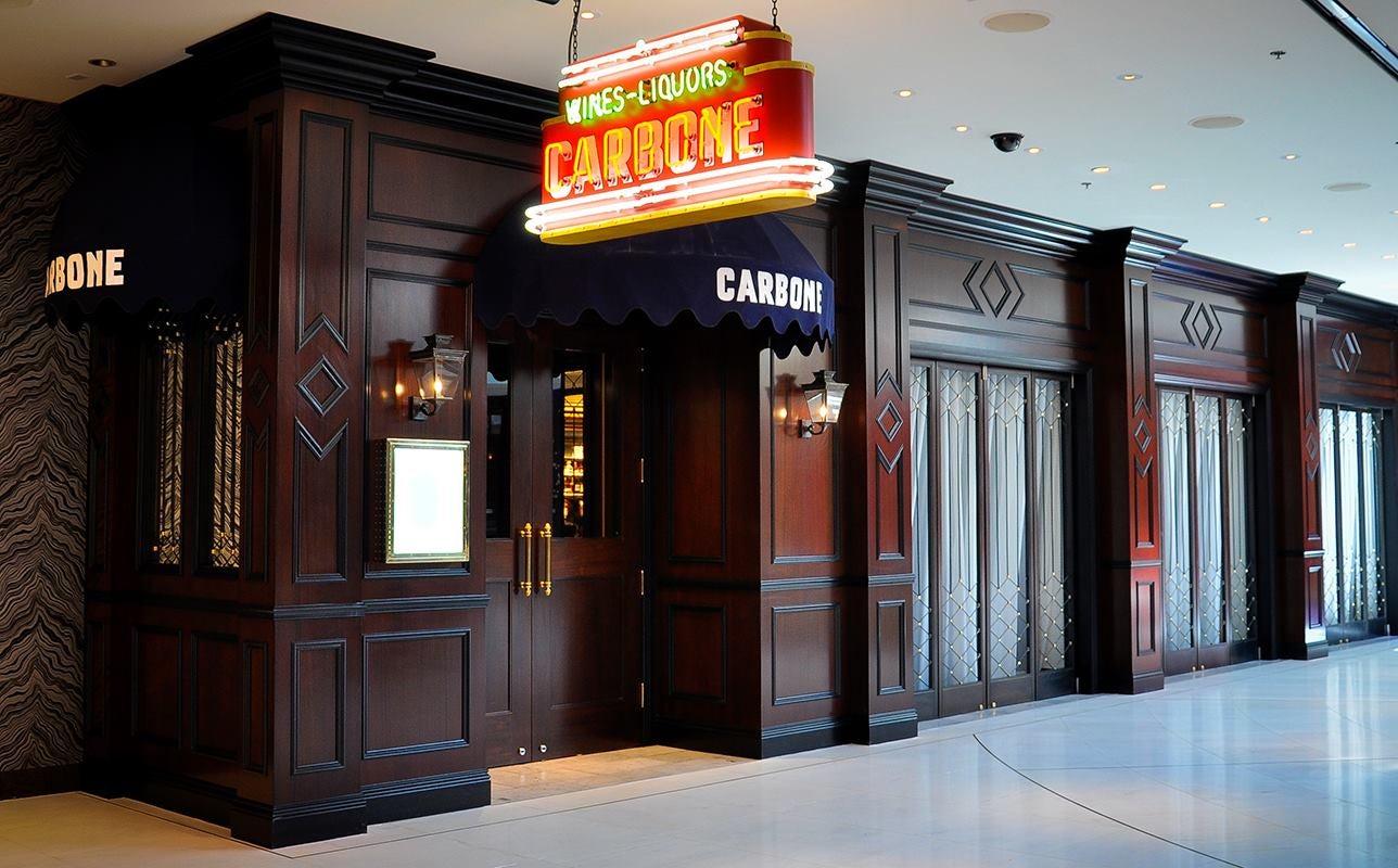 Wooden facade of a restaurant with a neon sign hanging in front of it