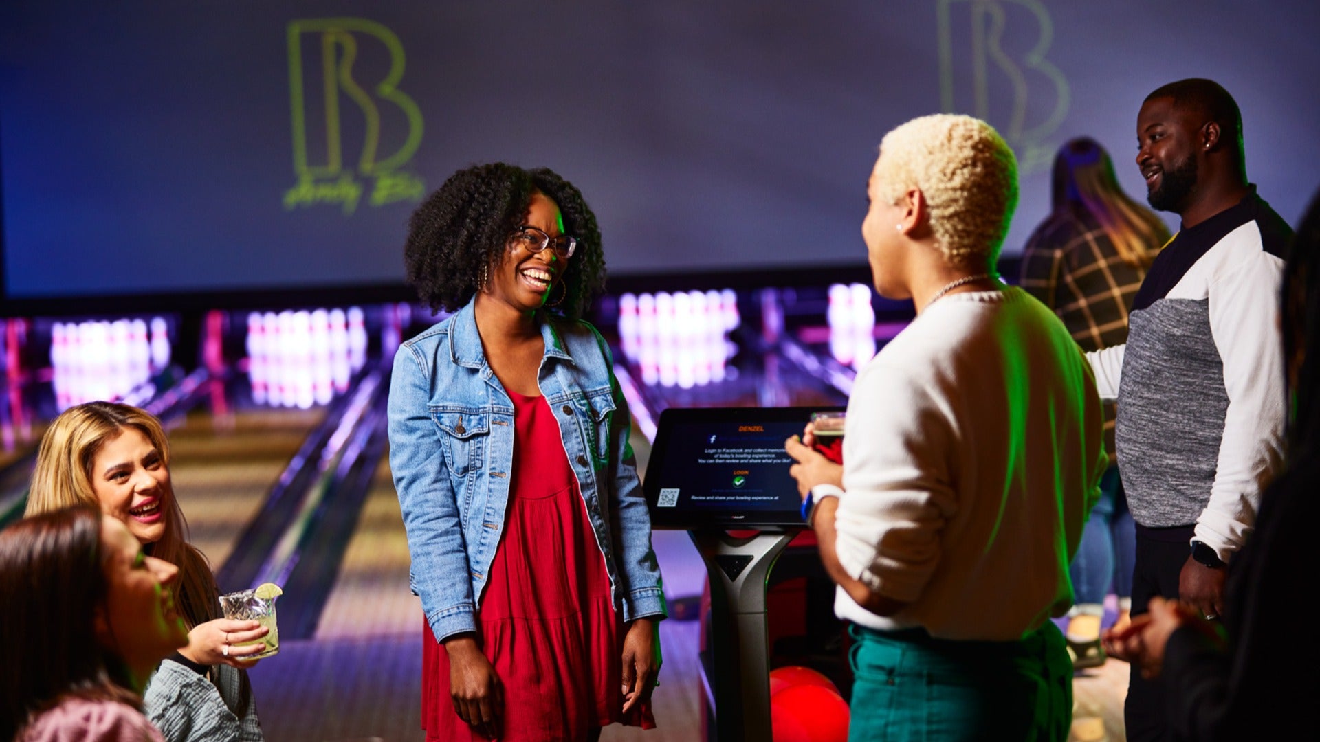 group of people talking and having fun at a bowling alley