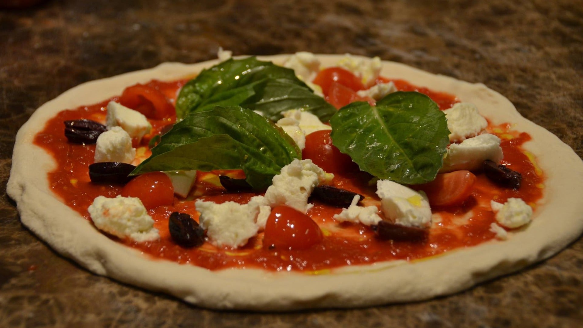 pizza with sauce, tomatoes, basil, and cheese