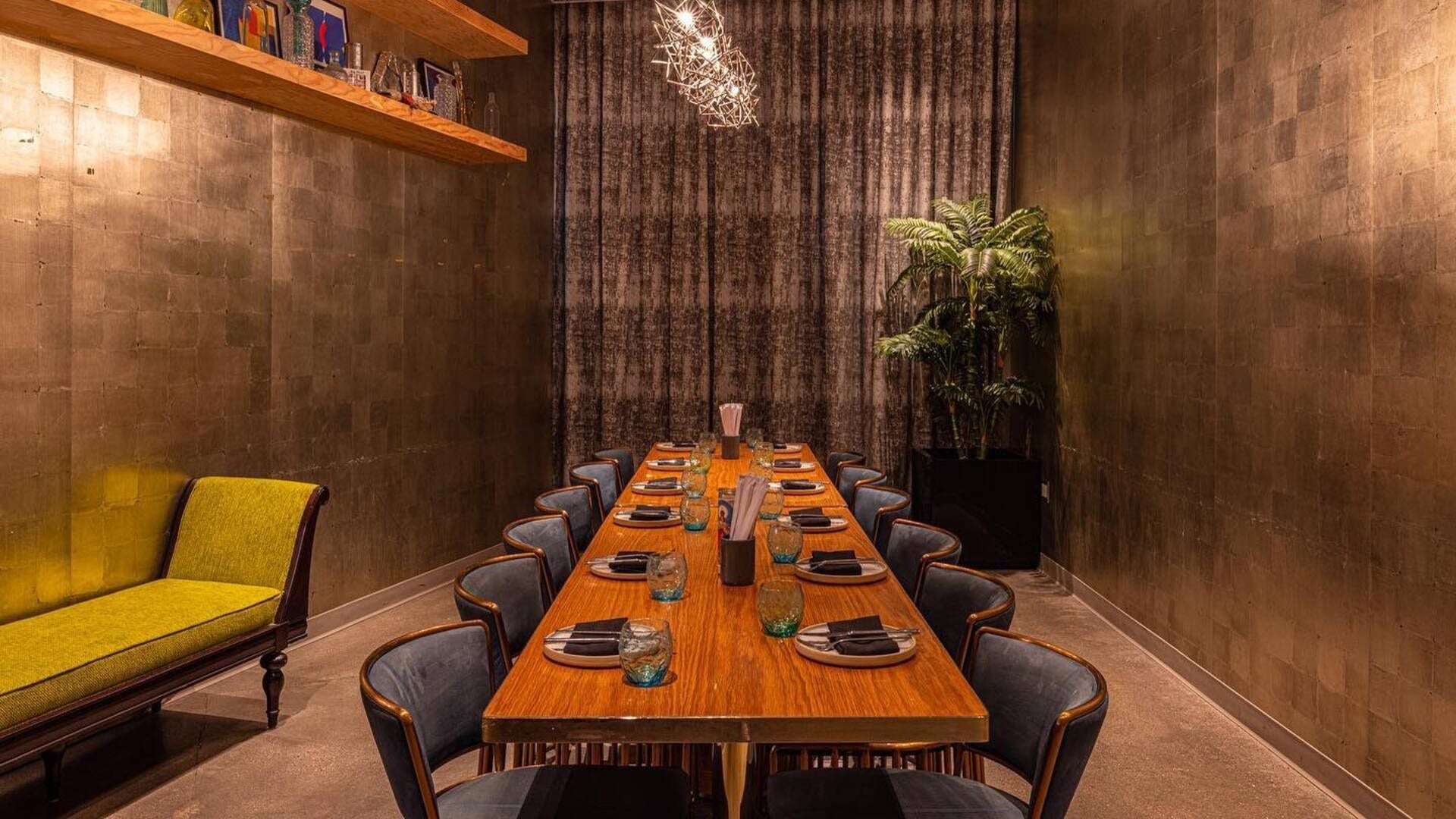 restaurant interior with long table, chairs, chaise, and plant on the side