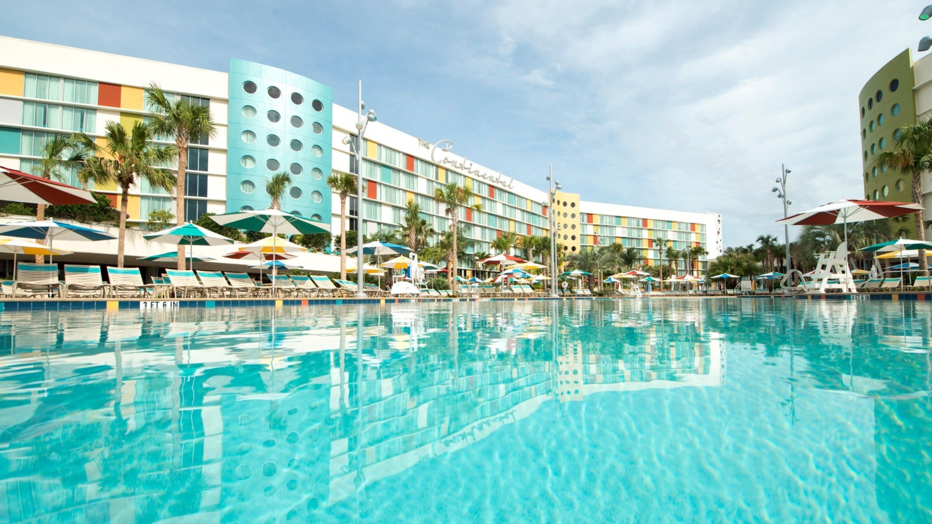 hotel exterior with a pool, cabanas, and lifeguard stand