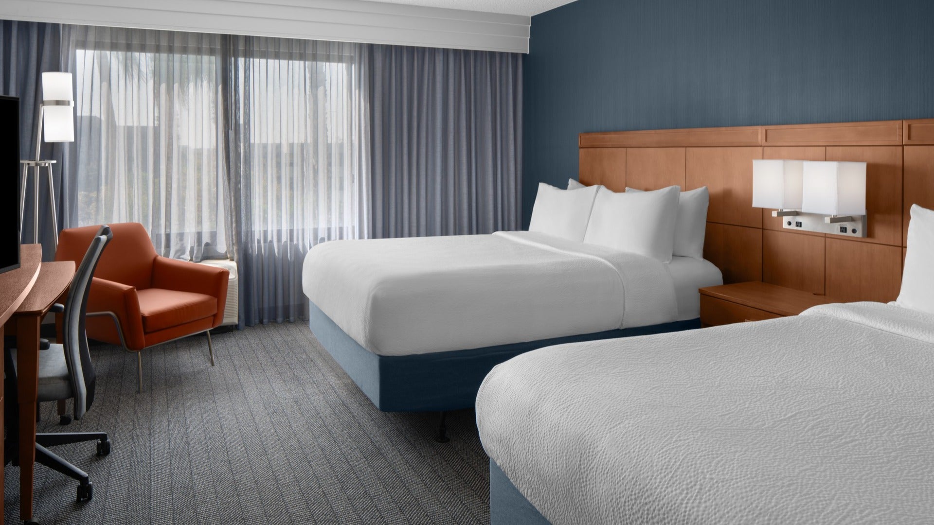 hotel room interior with beds, chair, work area, curtains