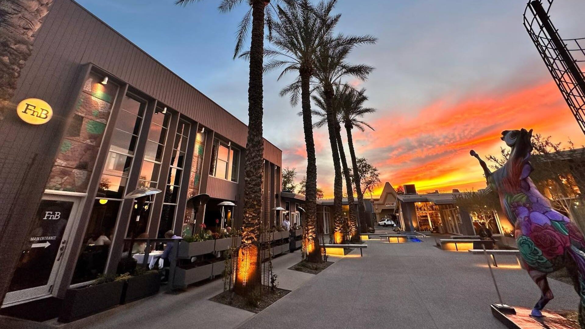 restaurant exterior with sculpture in front and palm trees