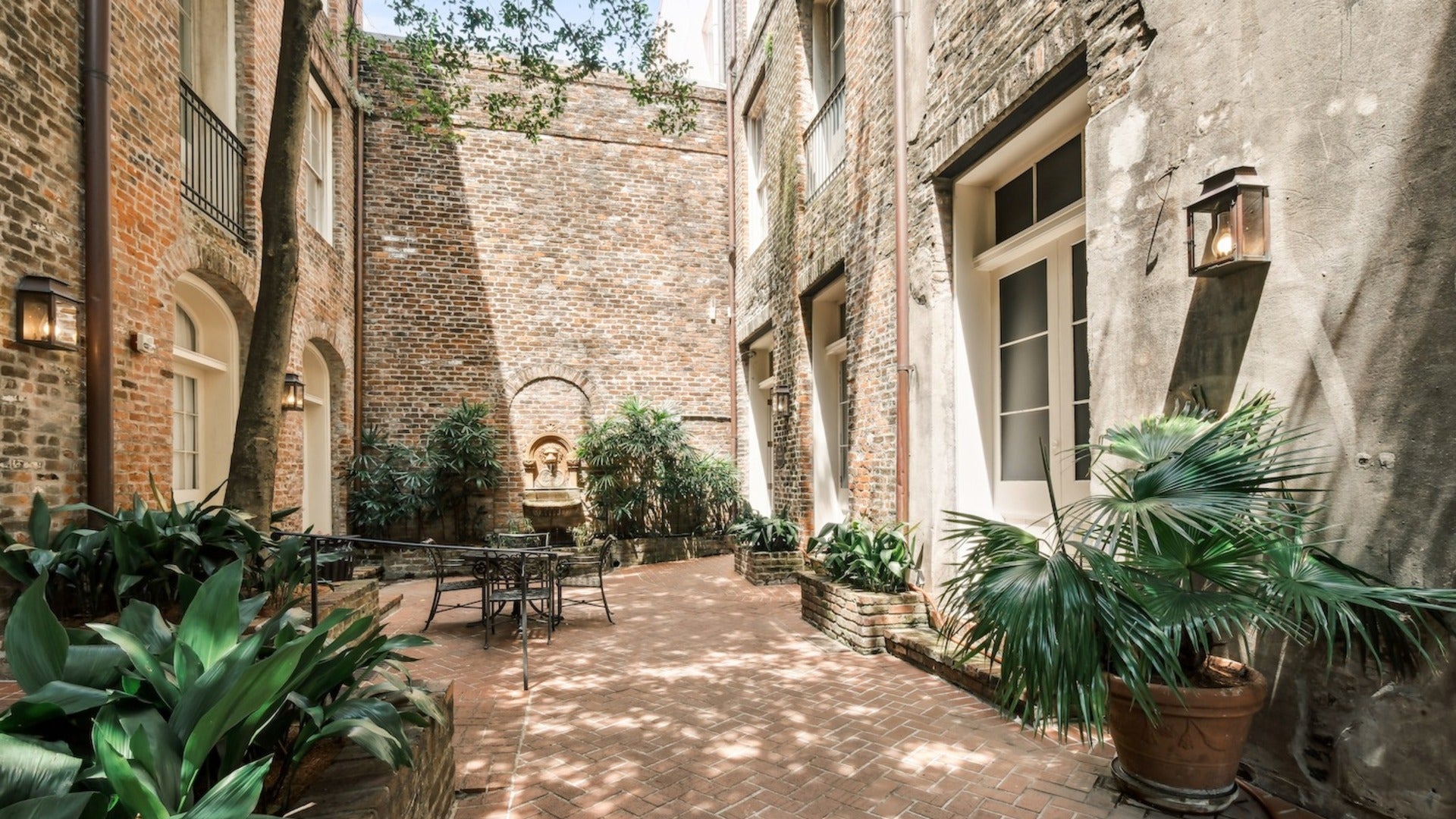 courtyard within a hotel with a tree and plants and table and chairs