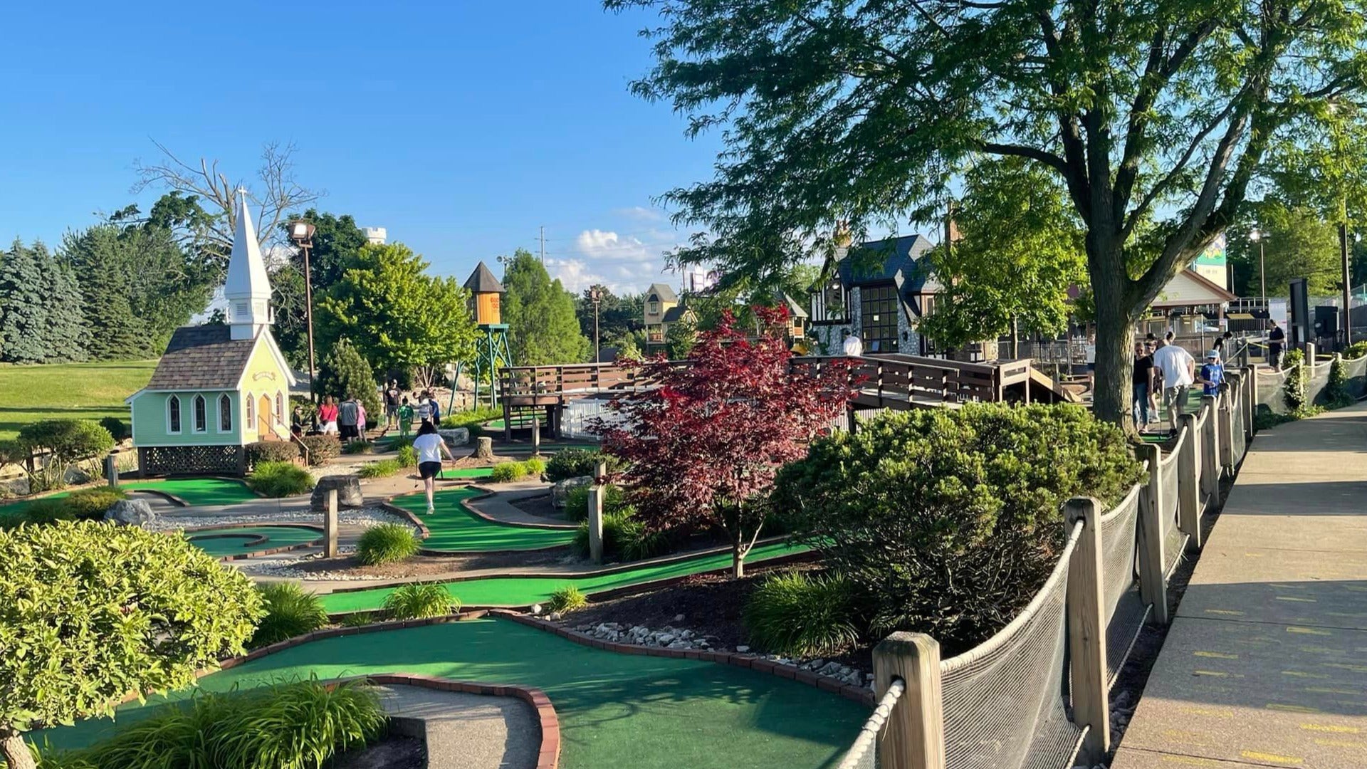 mini golf course with people playing, trees in the back