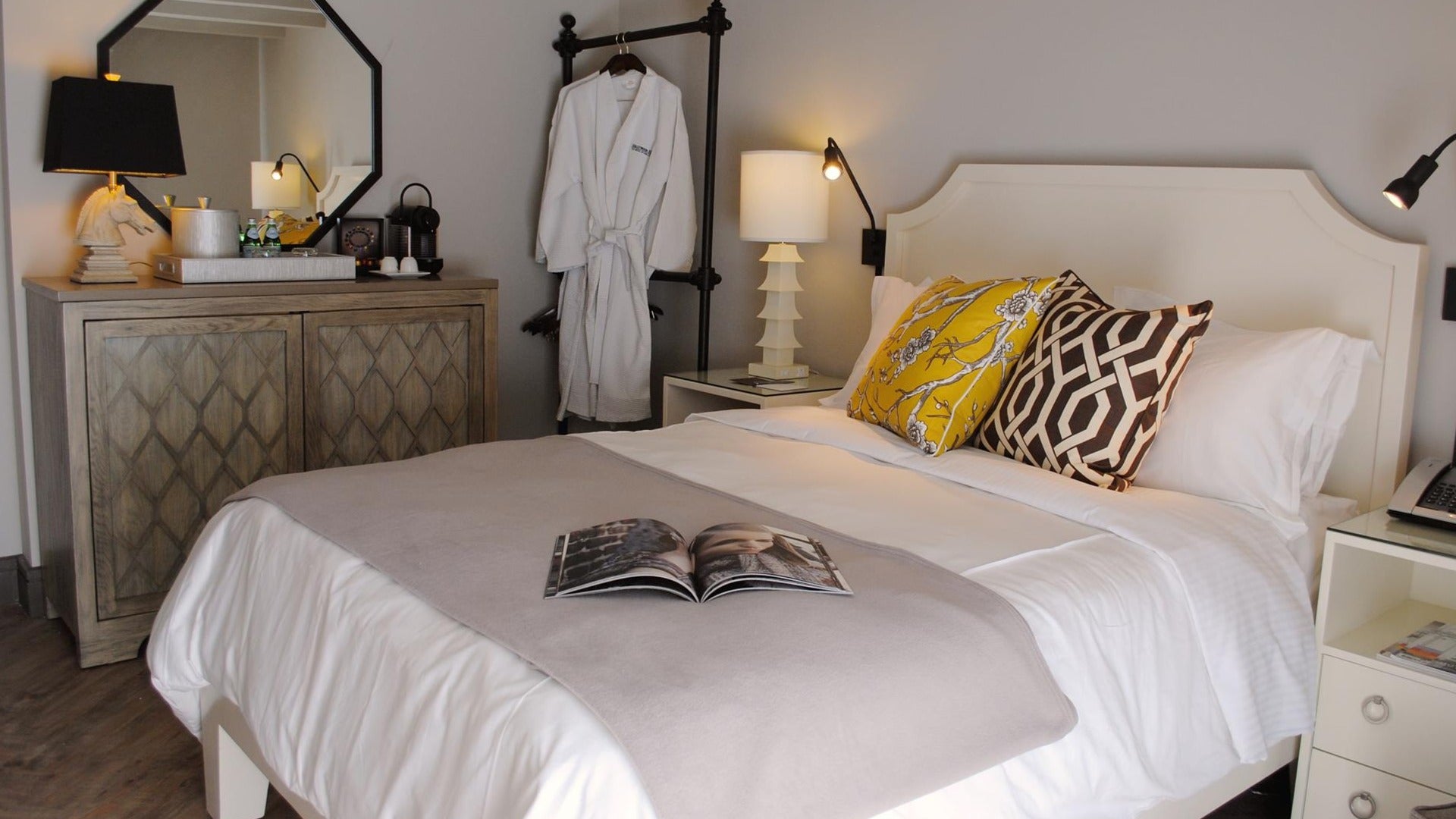 hotel room interior with bed, pillows, bathrobe, vanity, and lamps