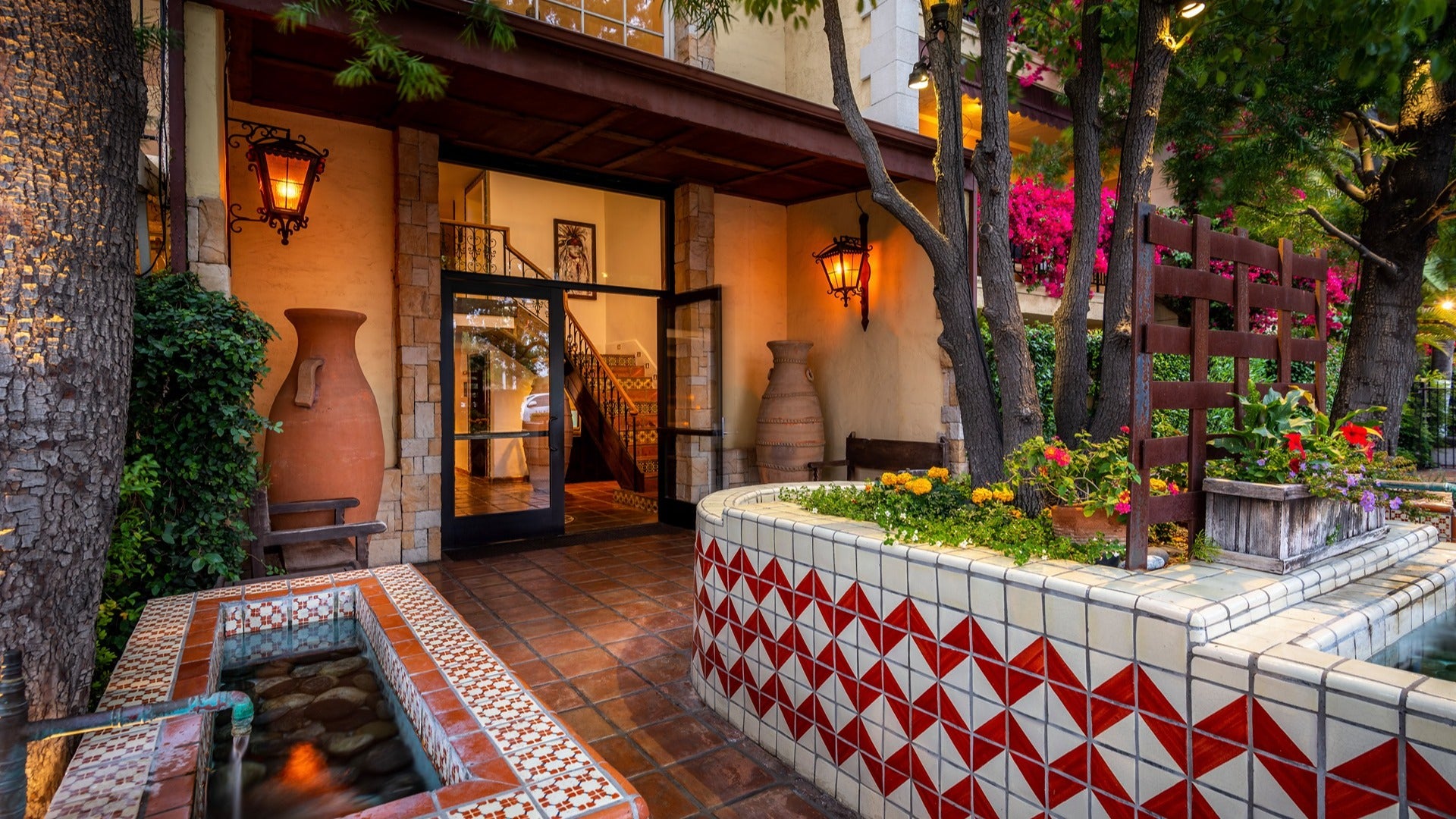 hotel exterior with colorful tiles, trees, flowers, glass doors and mini pond