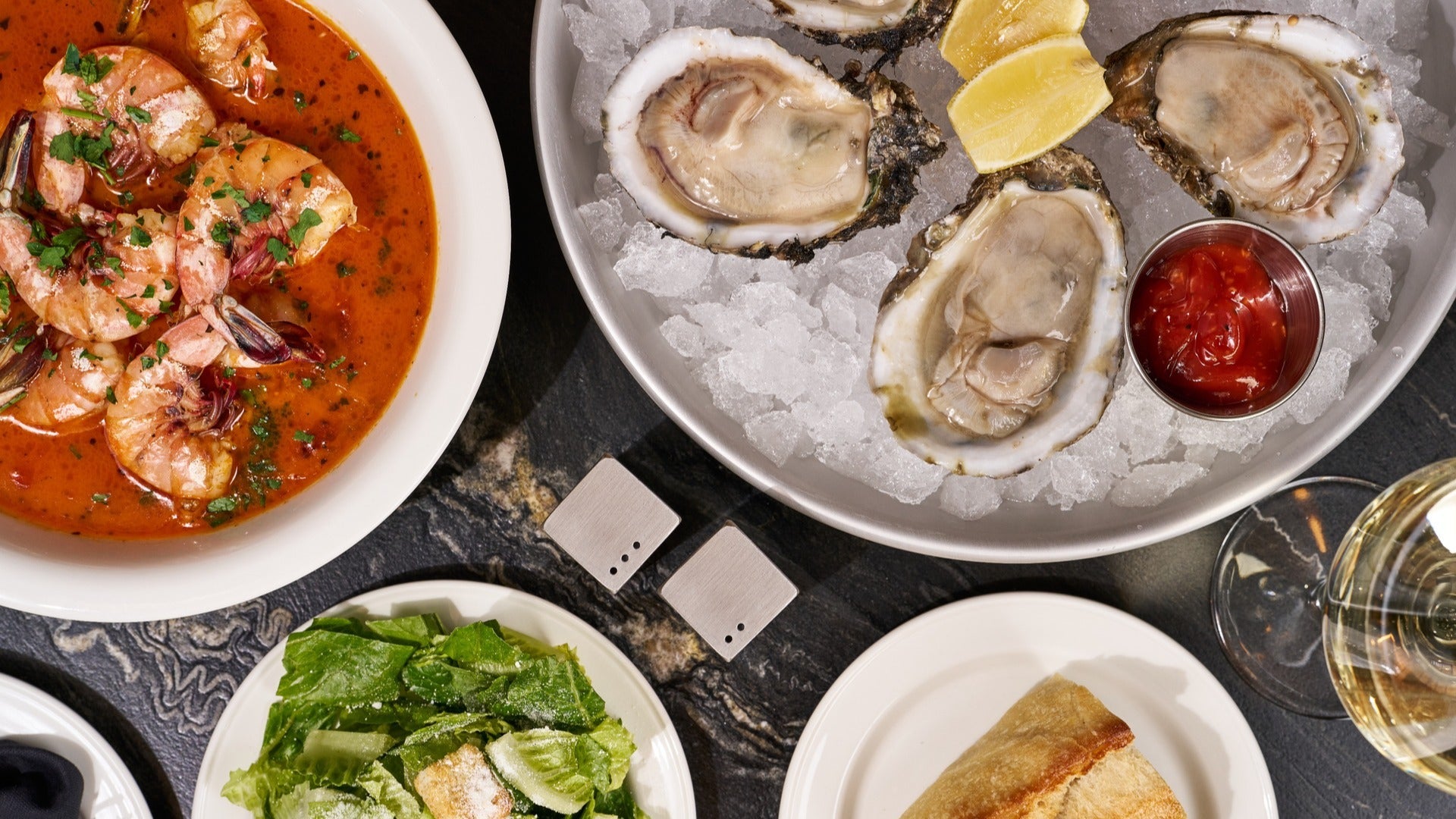 oysters, shrimp, and salad with a wine glass on the side