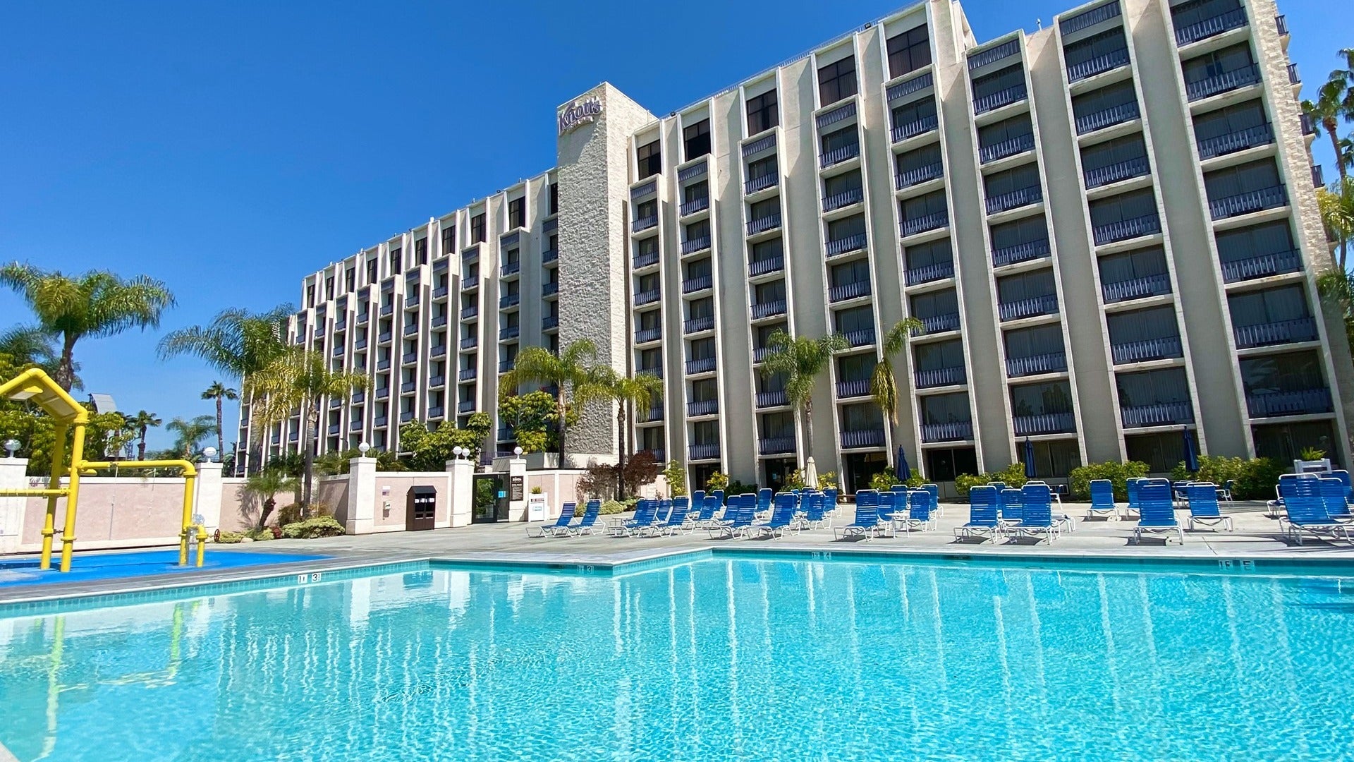 hotel exterior with pool, pool chairs, and a playground