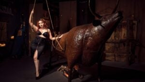 woman holding a torture device in a musuem, bull on the side