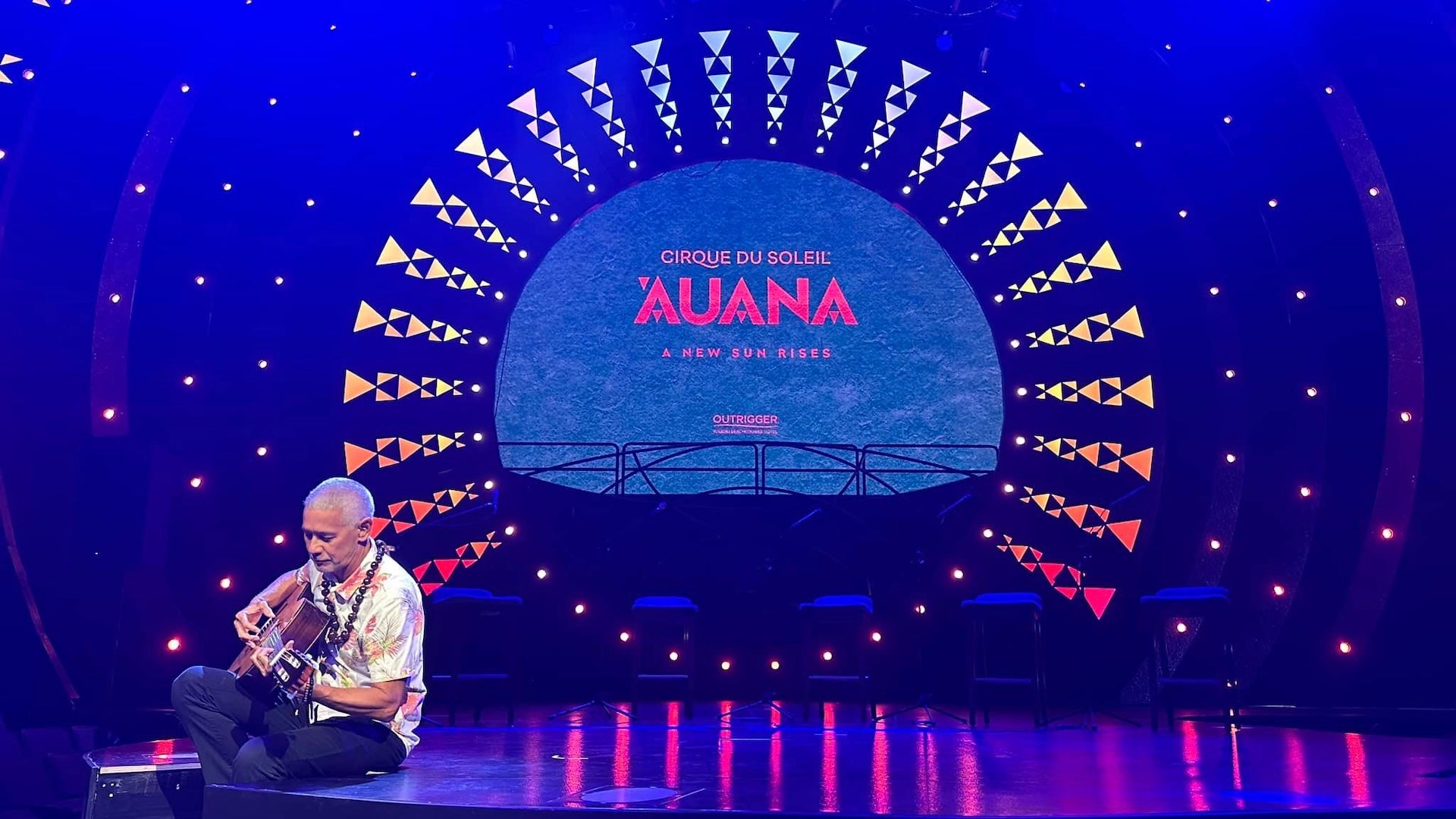 a man with his guitar sitting on stage