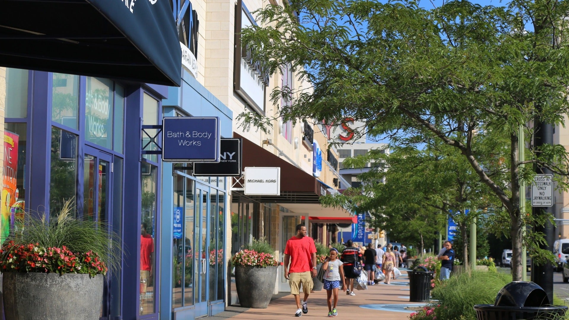 line of stores with people shopping and trees on the sidewalk